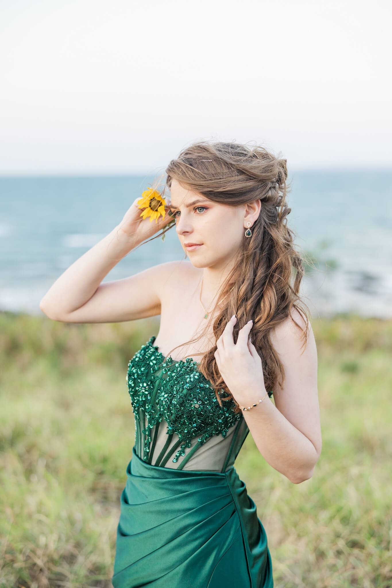 High School senor in an emerald green dress from Oak and Valentine, standing on a hill near the ocean. Photographed by Julie-Anne Photography.