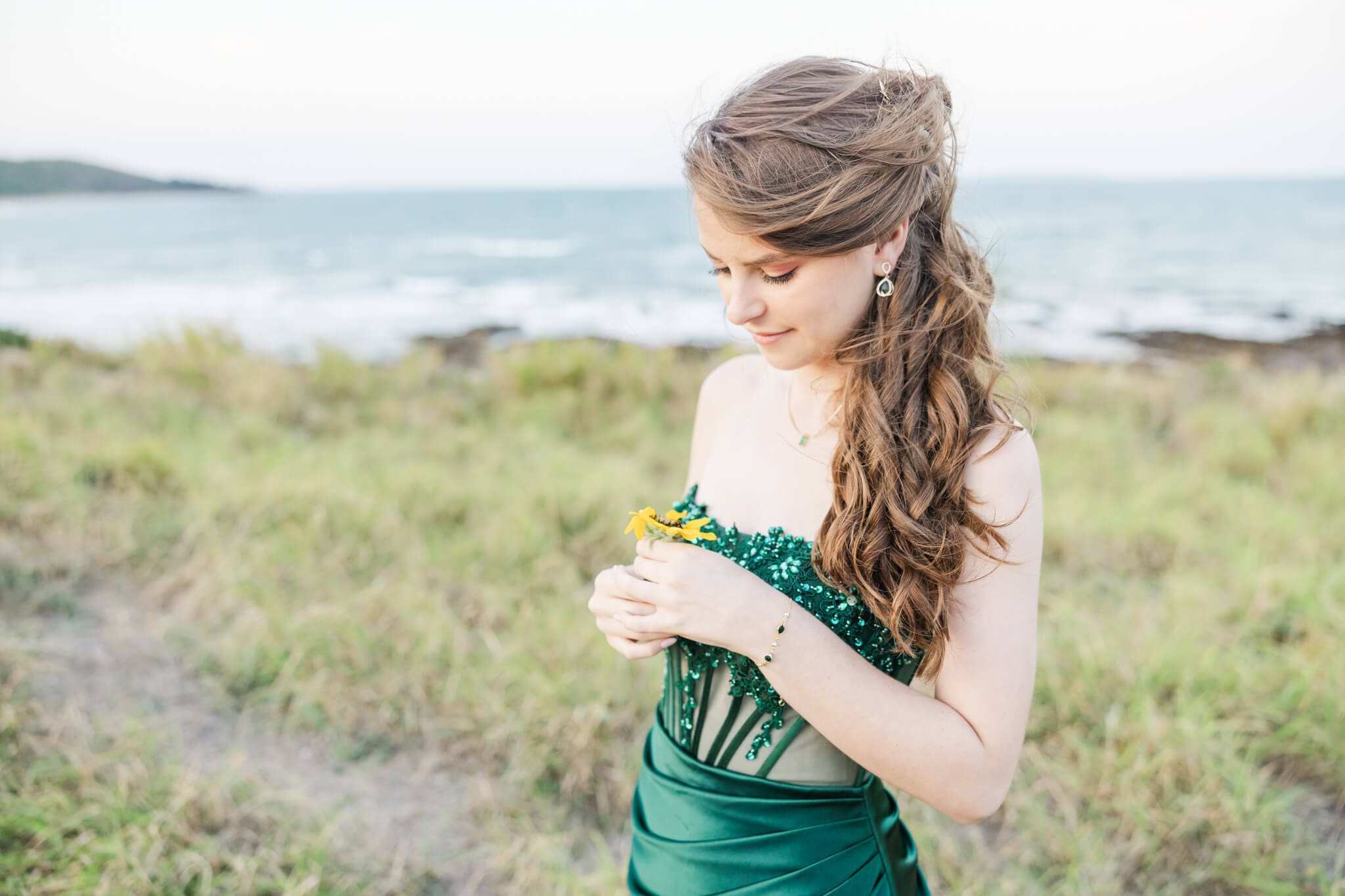 Gorgeous formal photo of high school senior in a green Oak and Valentine formal dress Rockhampton, at a location near the ocean.