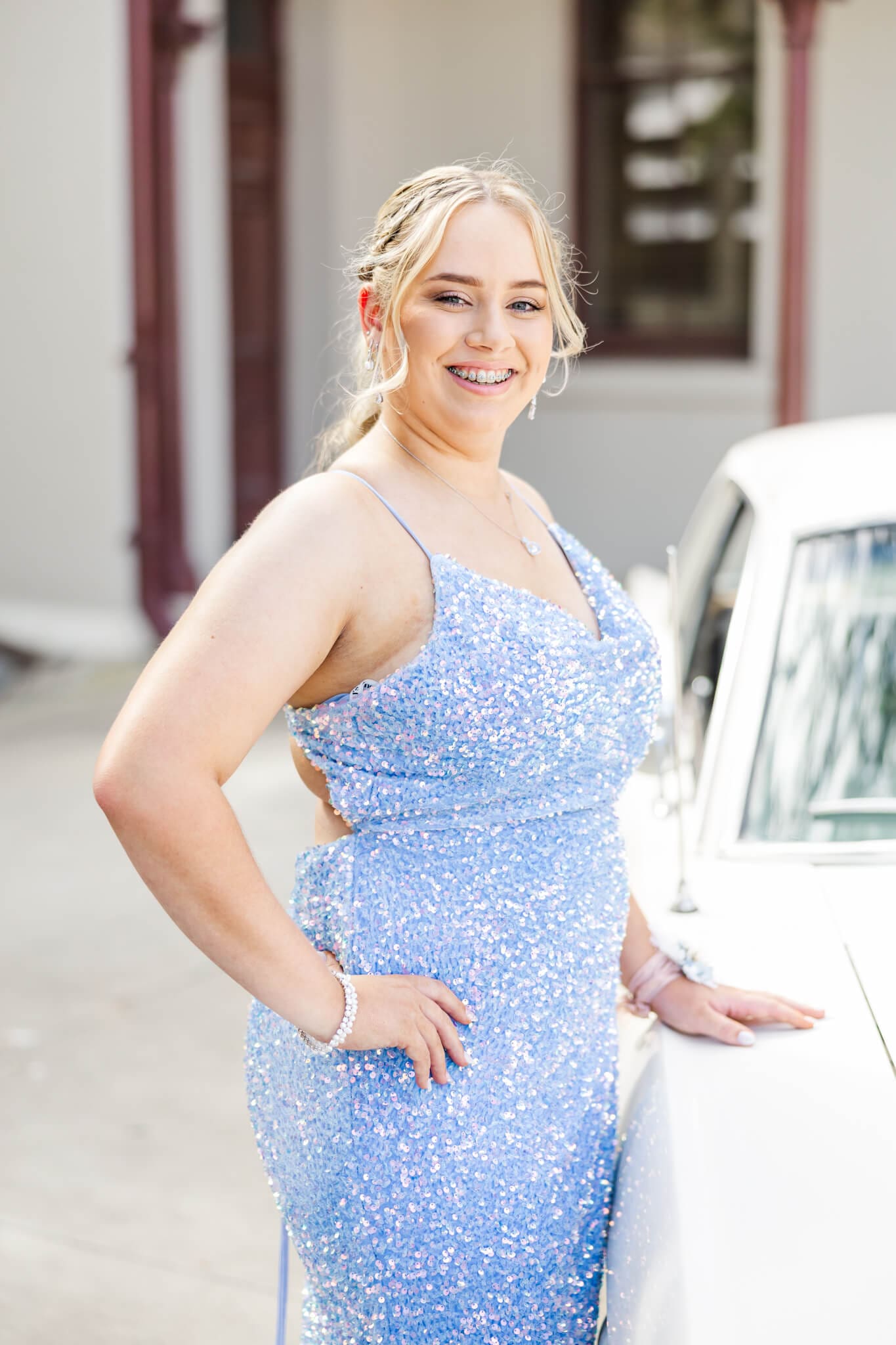 Girl wearing a sky blue dress, standing near a cream vintage car for her formal photos, East Street, Rockhampton.