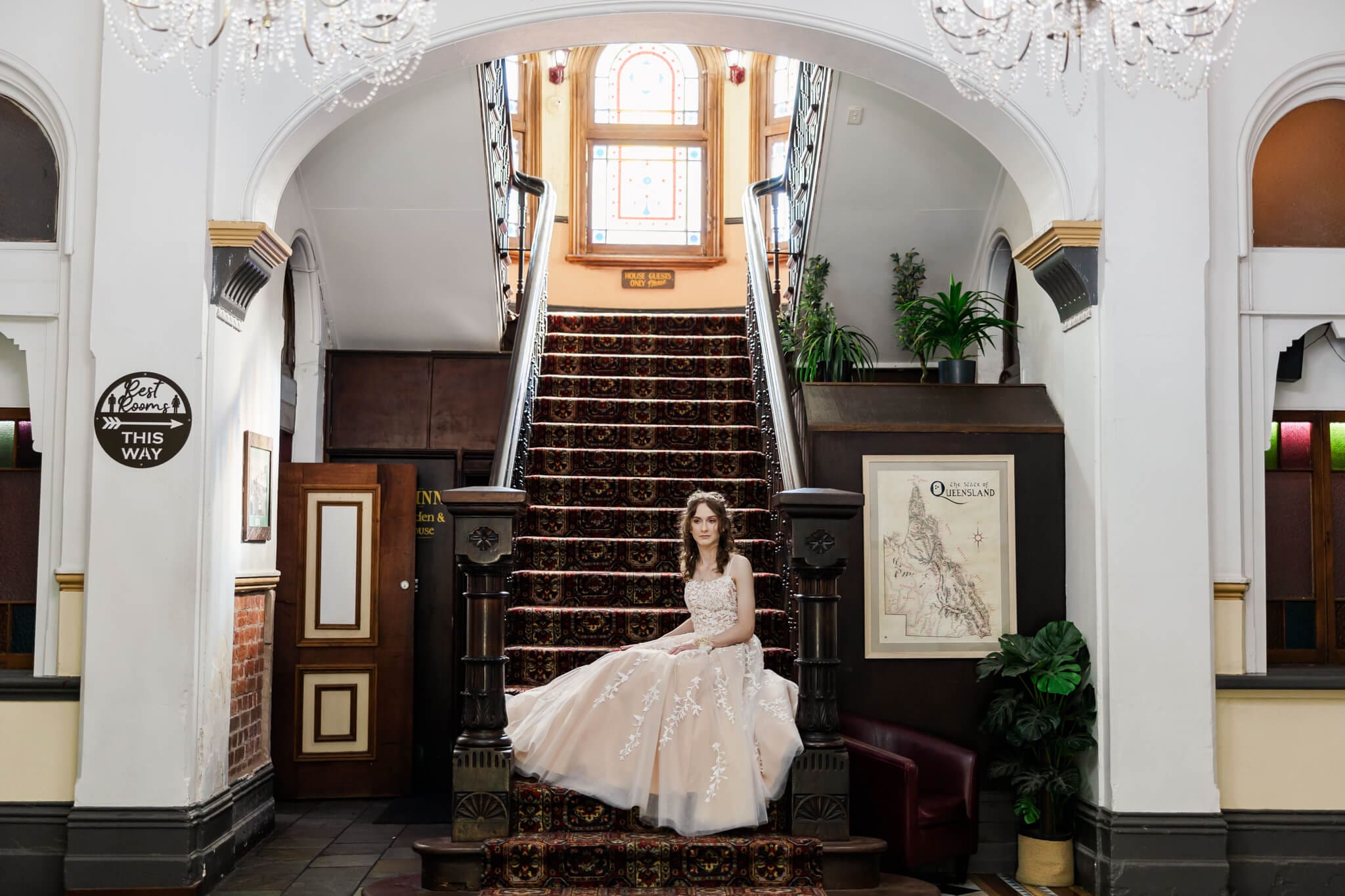 Photo of girl graduate sitting at the bottom of a historical staircase, dressed in a formal dress by Gossip Gowns.
