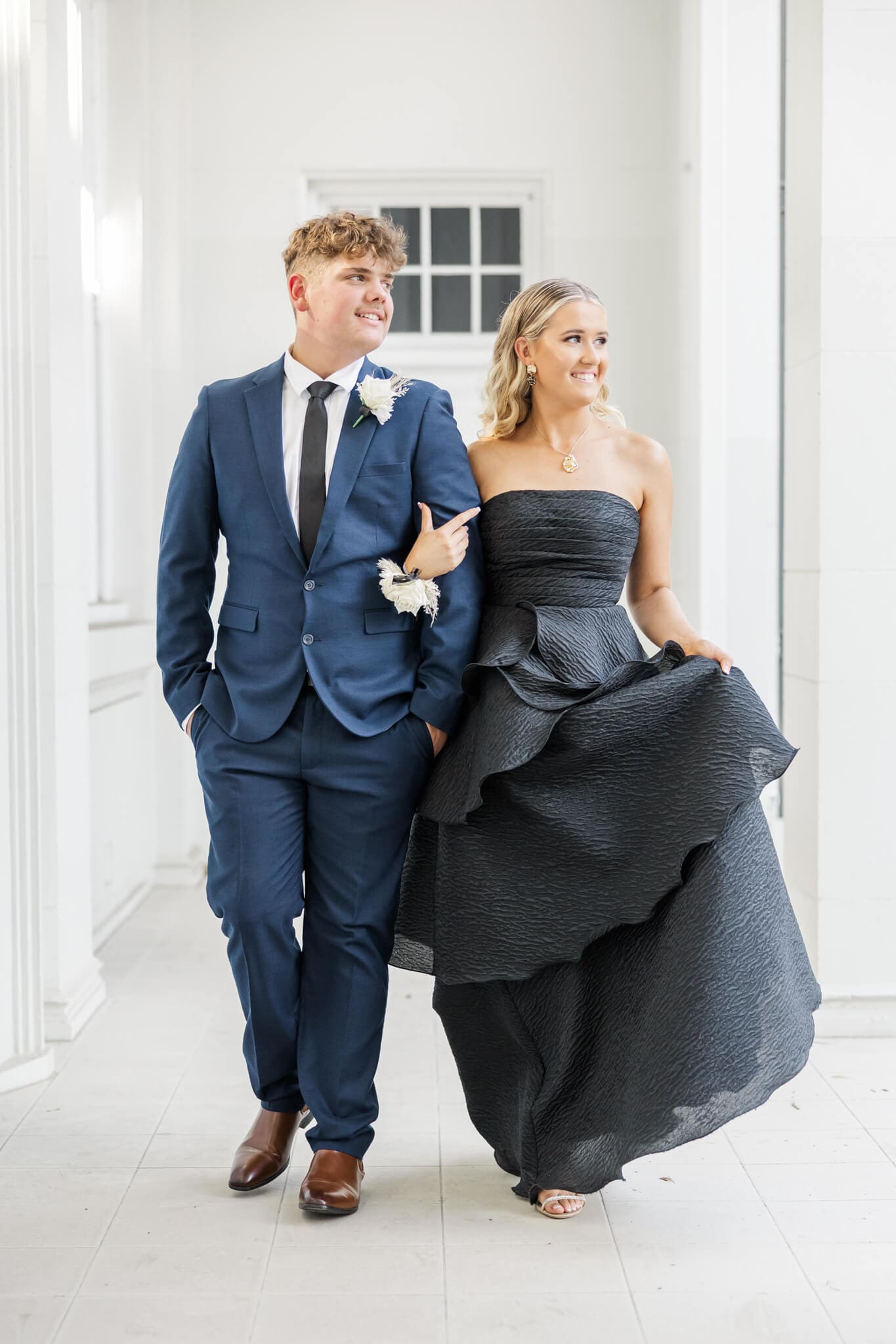 Formal photos of a girl in a black formal dress, Rockhampton, walking beside her partner dressed in blue.