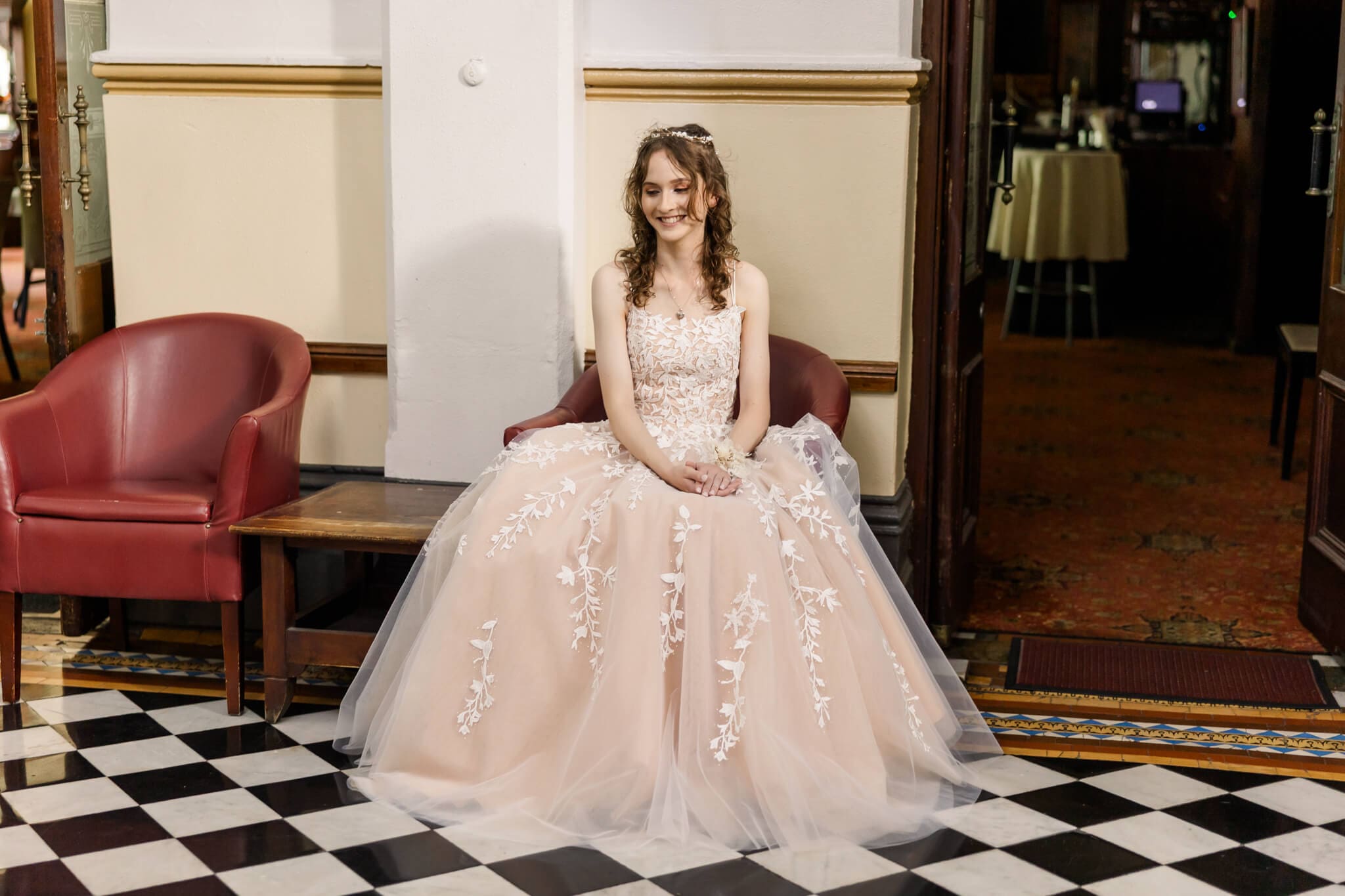 Girl posing for her formal, seated and dressed in a formal dress from Gossip Gowns. Photographed by Julie-Anne Photography.