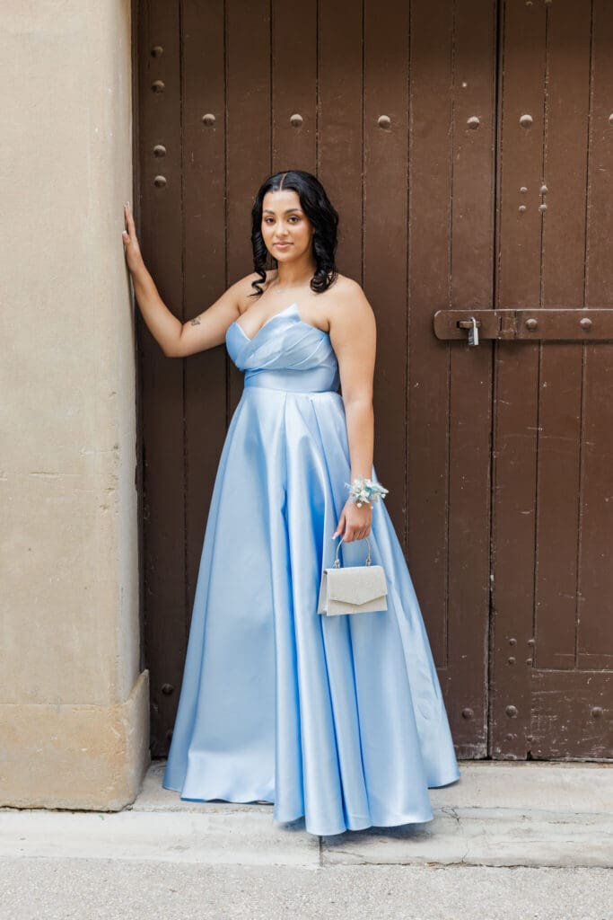 High school senior on her formal day, dressed in a sky blue dress, posing on a historical brown door at the Customs House, Rockhampton, Queensland.