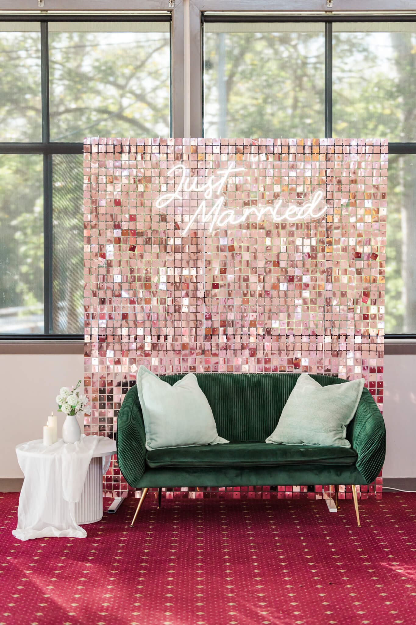 Pink photo back drop with a green couch in front of it for use at a wedding reception.