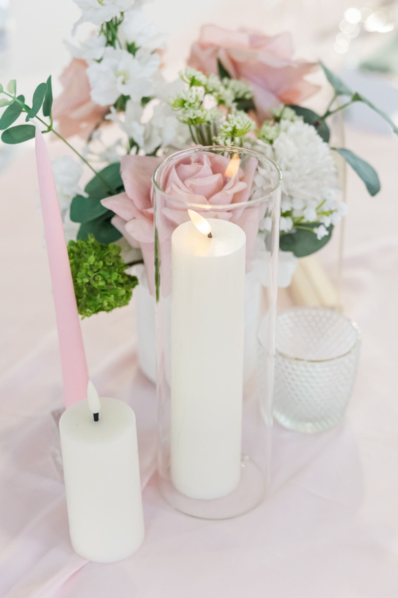 White candle lit next to a beautiful floral arrangement, styled by Little List Co. Captured by Julie-Anne Photography.