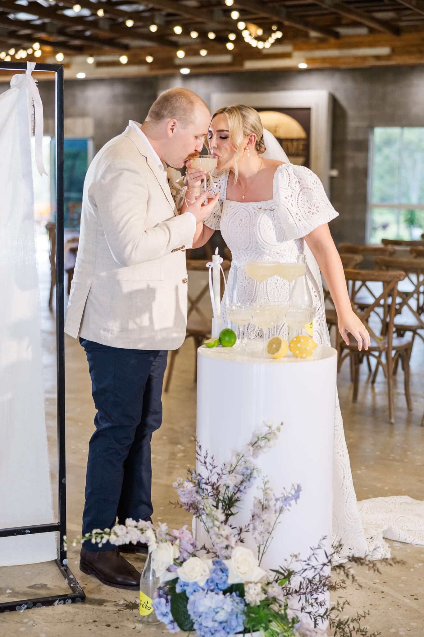 Bride and groom drinking from champagne tower glasses.
