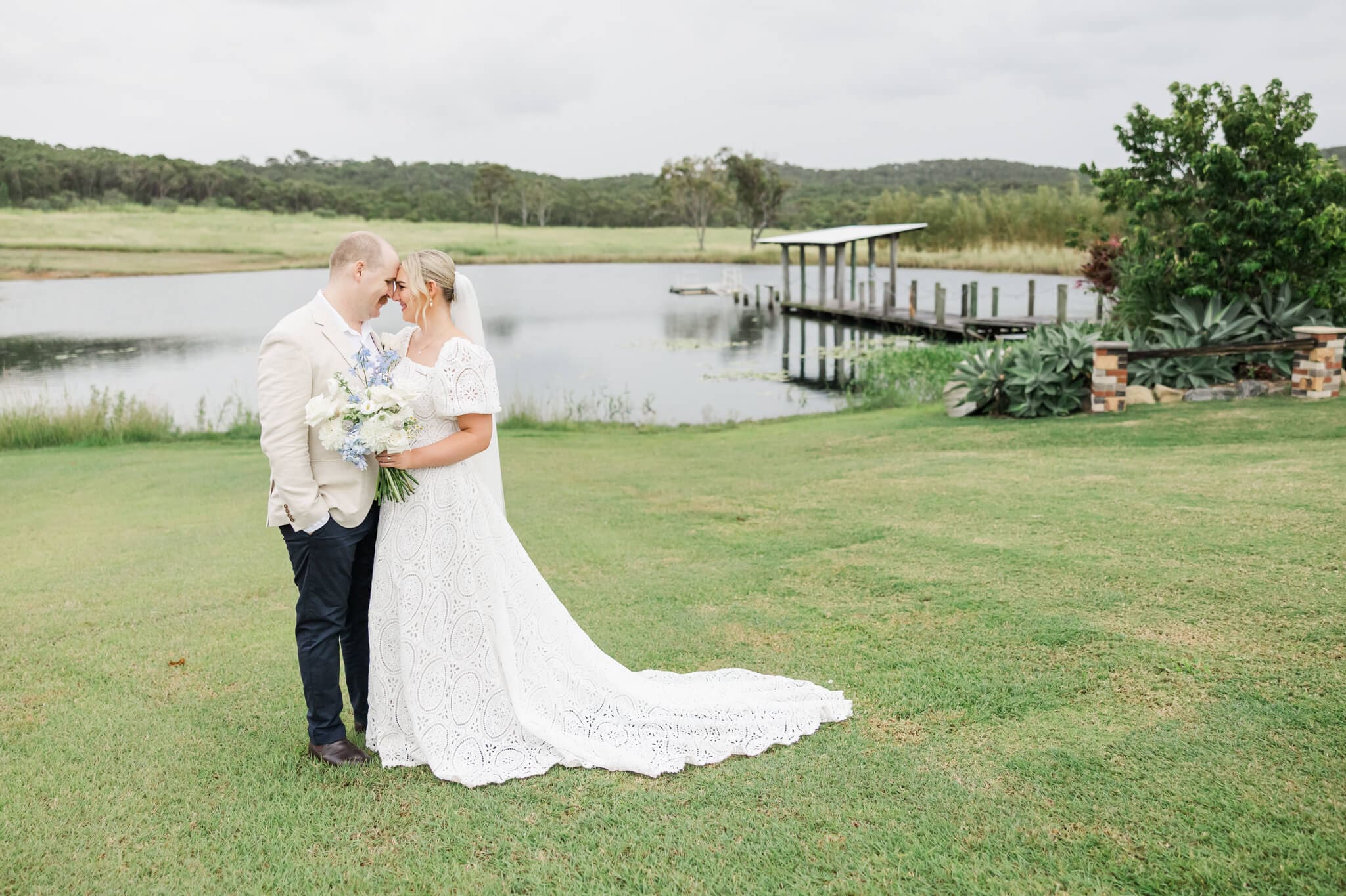 Bride and Groom pose in front of the lake at The Salty Lime Co. wedding venue.
