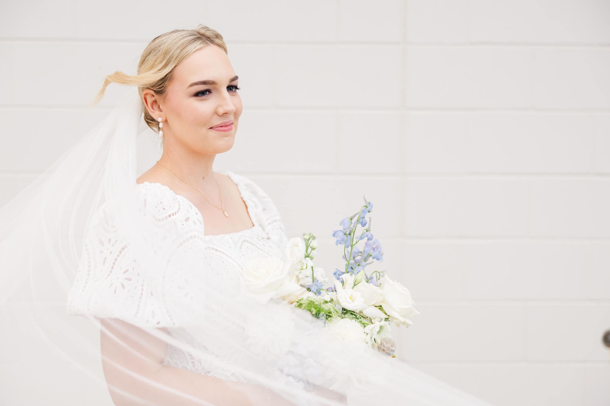 Bride reflecting with a blue and white bouquet in her hands.
