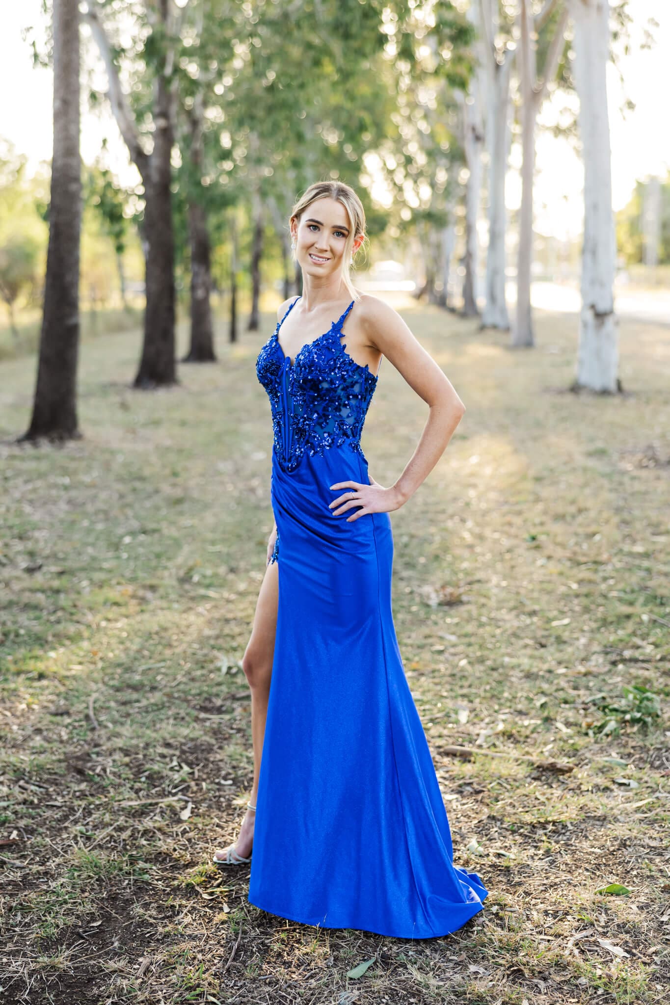 Stunning Formal dress from One Honey, modeled by a blonde haired slim girl in a corridor of trees.