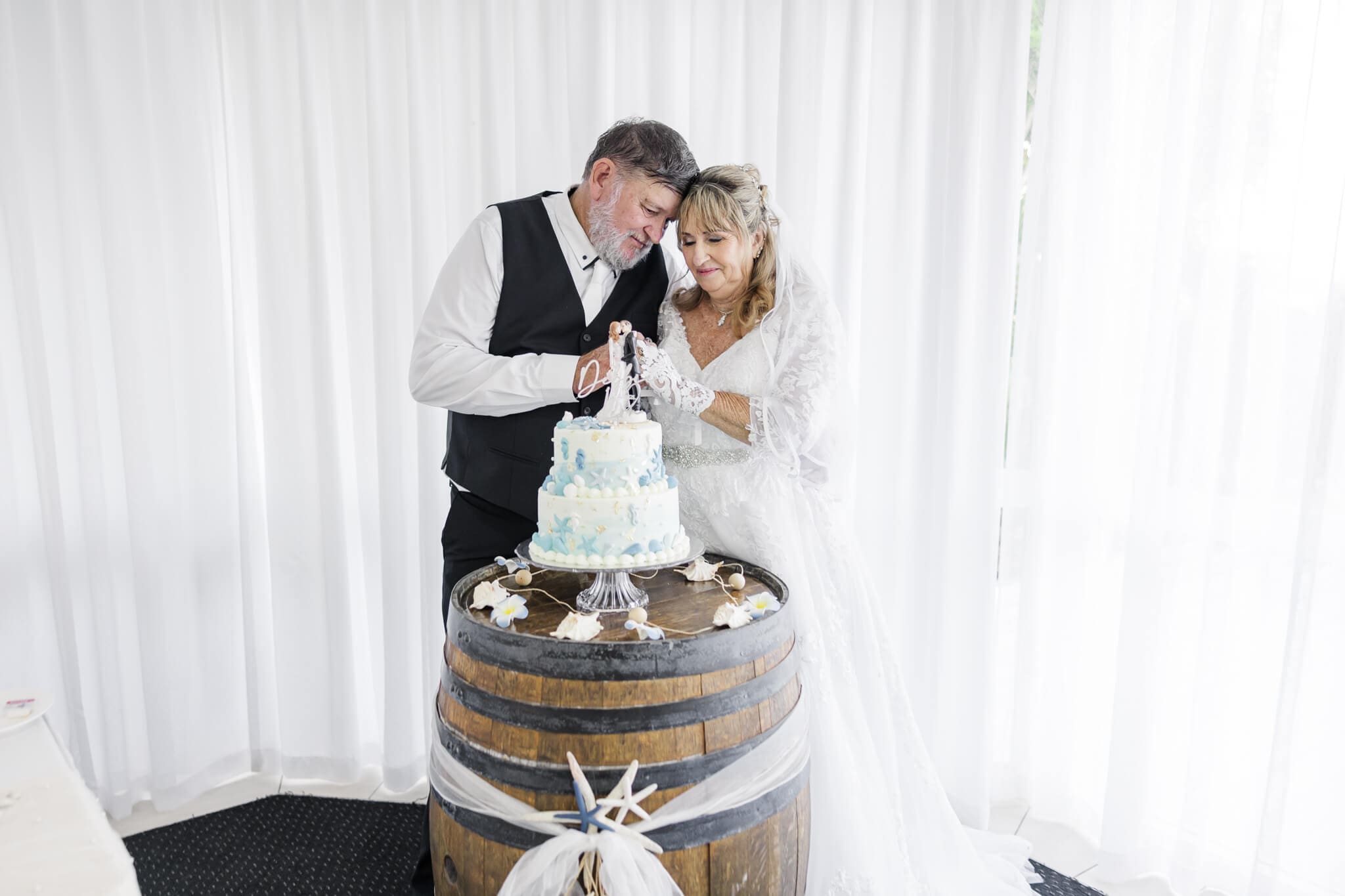 Bride and Groom cut their cake at their wedding reception. Wedding venue is Beaches Restaurant Yeppoon.