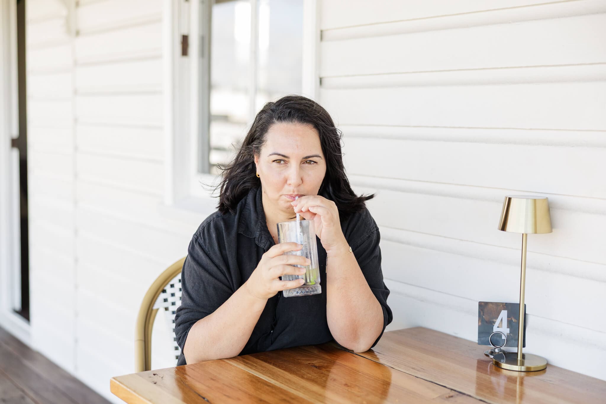 Wedding planner, Gina, takes a sip while sitting at a table, ready to chat about your wedding! Captured by Julie-Anne Photography.