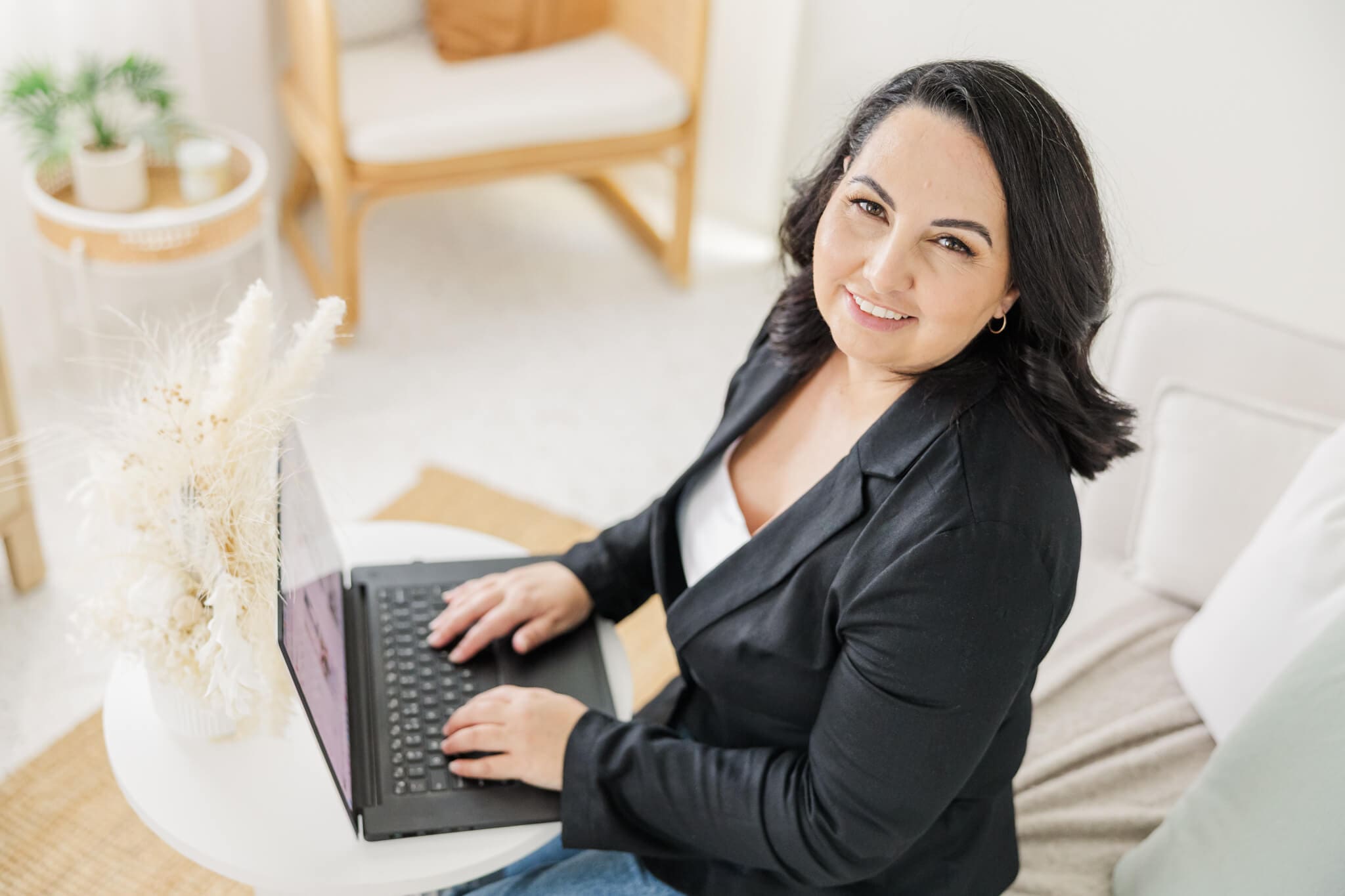 A woman dressed in black posing with a laptop. She is a wedding planner from Yeppoon Queensland.