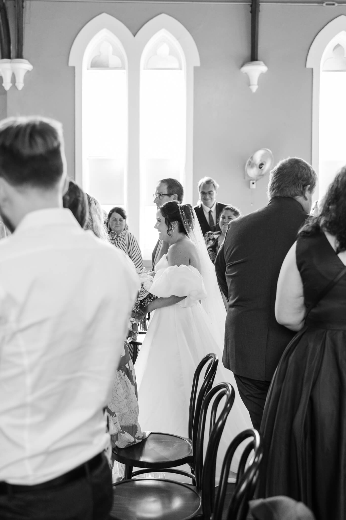 Black and white portrait of the bride walking down the aisle at the Church Events Venue in Rockhampton. Captured by Julie-Anne Photography, Rockhampton Wedding Photographer.