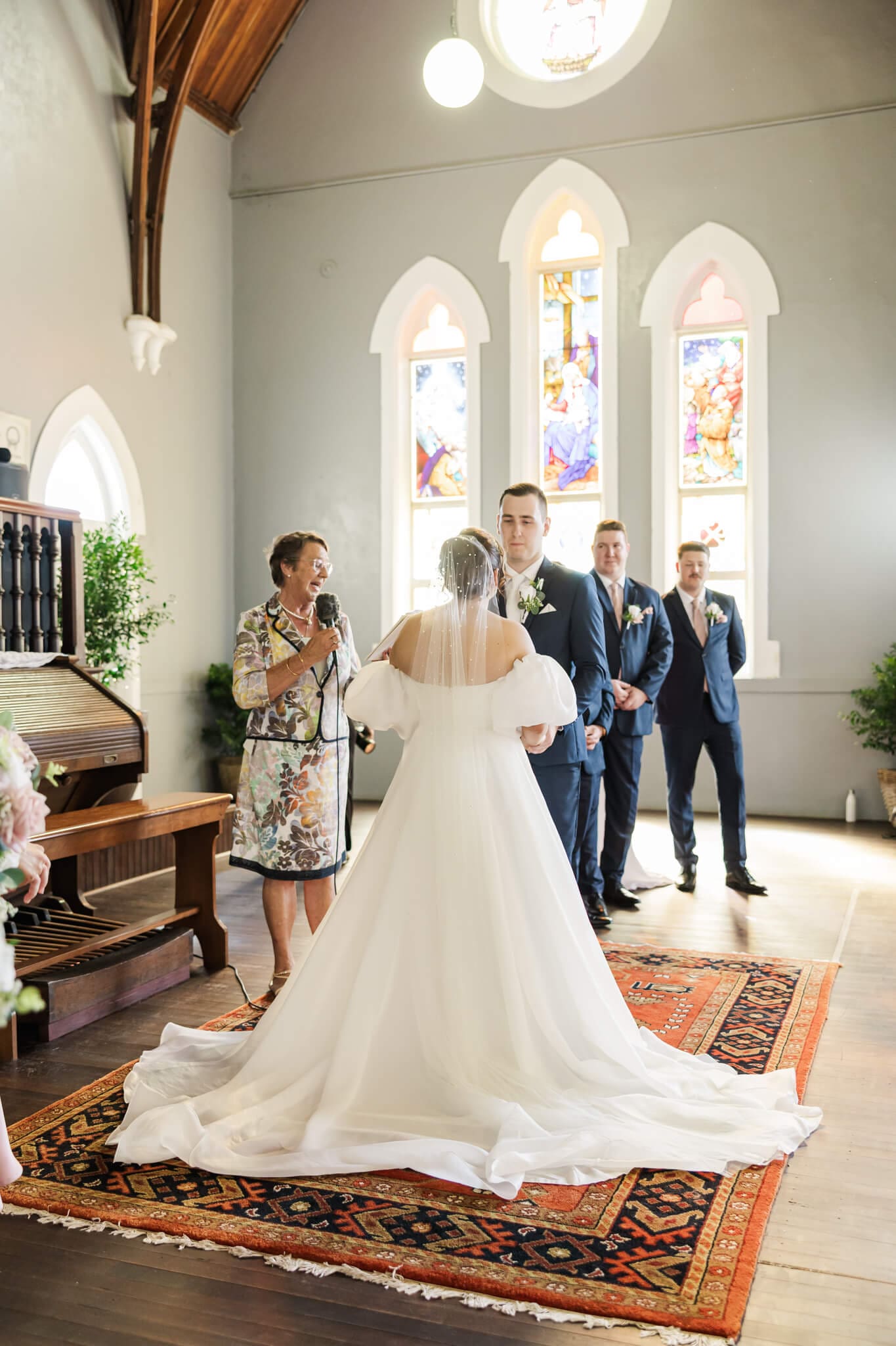 Beautiful ceremony settings at the Church Events Venue in Rockhampton. Stained glass windows letting in natural light while the bride and groom exchange wedding vows.