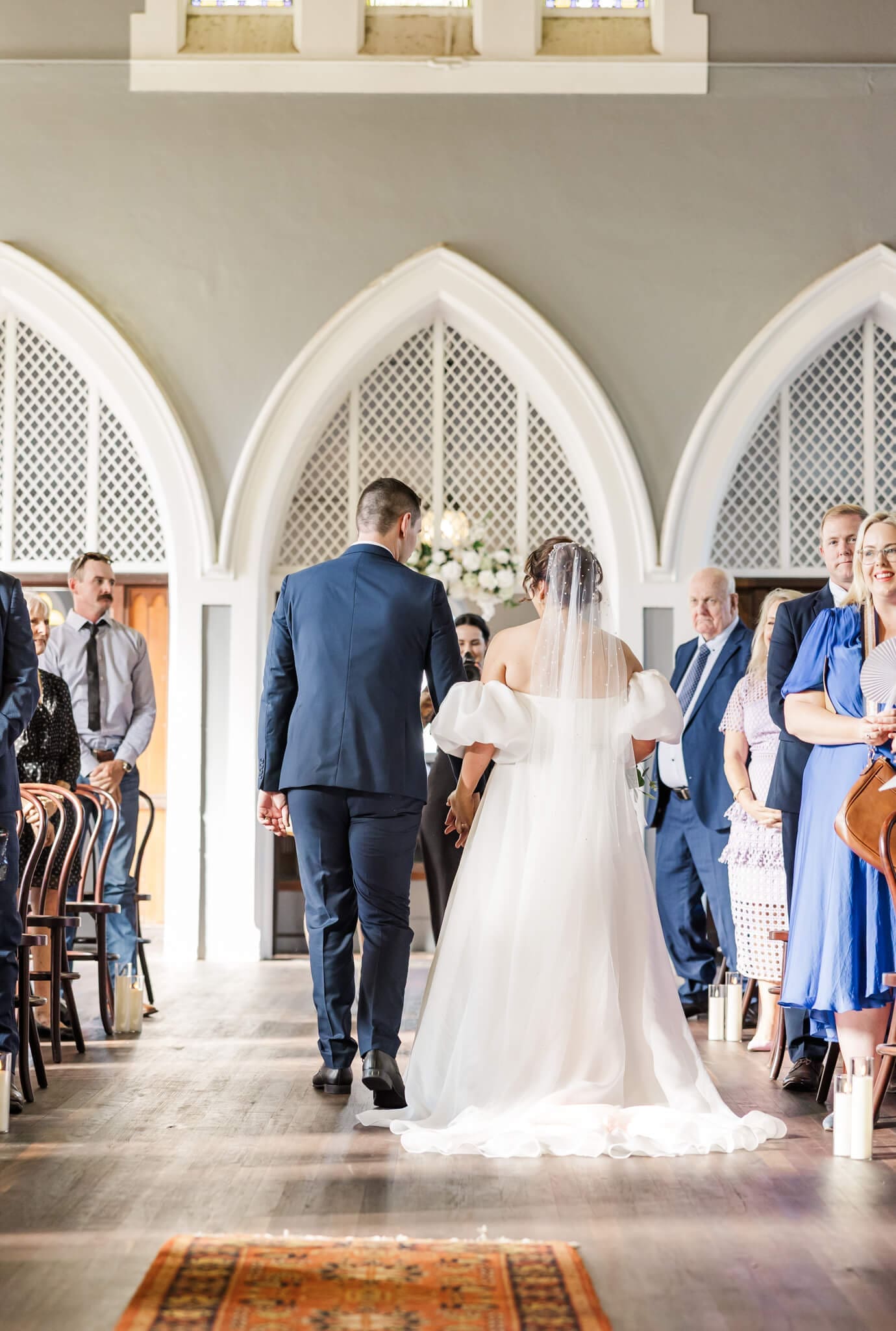 The recessional after the wedding ceremony, back view of the bride and groom walking down the aisle after their marriage.