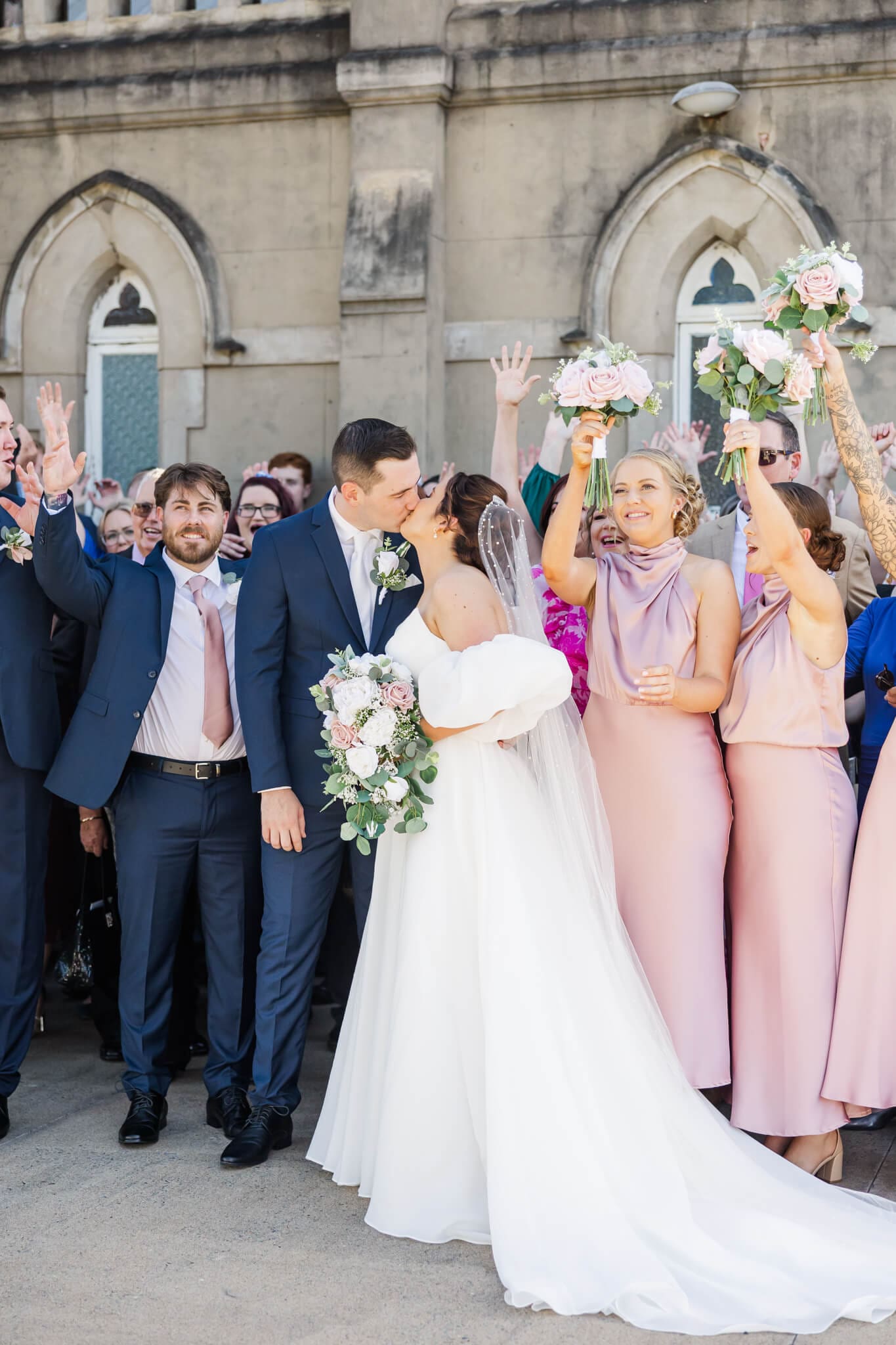 Celebrating their wedding, the bride and groom share a kiss with their friends and family at the Church Events in Rockhampton.