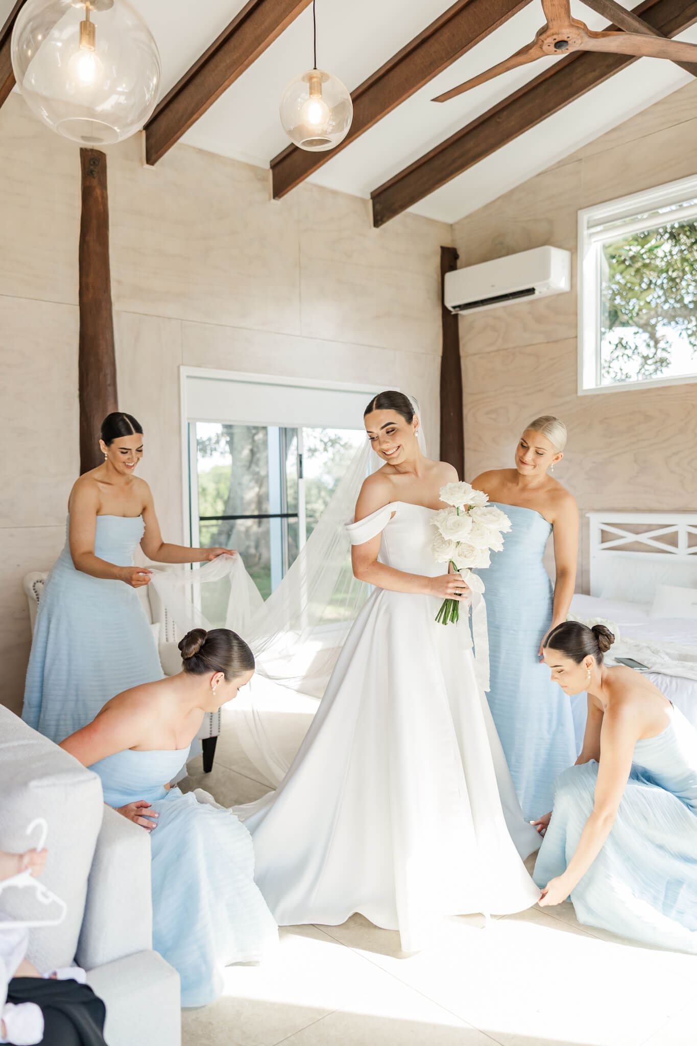 Wedding preparation with the girls. A beautiful bride prepares for her wedding with her 4 bridesmaids dressed in blue, in the Hilltop Chalet at The Woodbury Lookout wedding venue near Yeppoon. Captured by Julie-Anne Photography.
