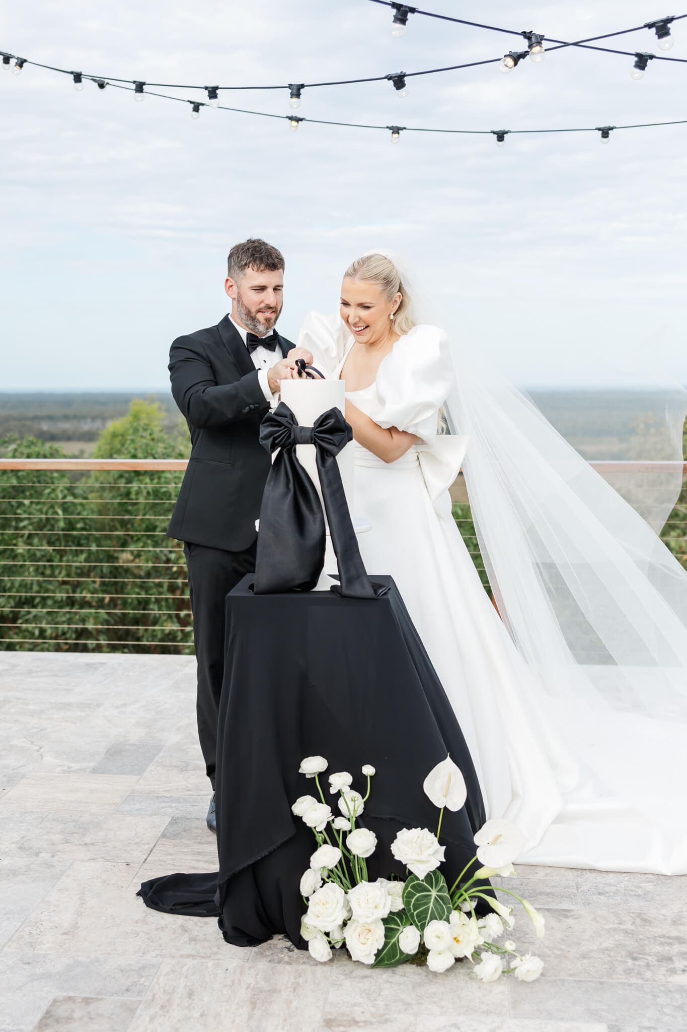 Bride and Groom cut their cake at Ambrym Estate Yeppoon on a beautiful elevated concrete area overlooking a beautiful view towards the ocean