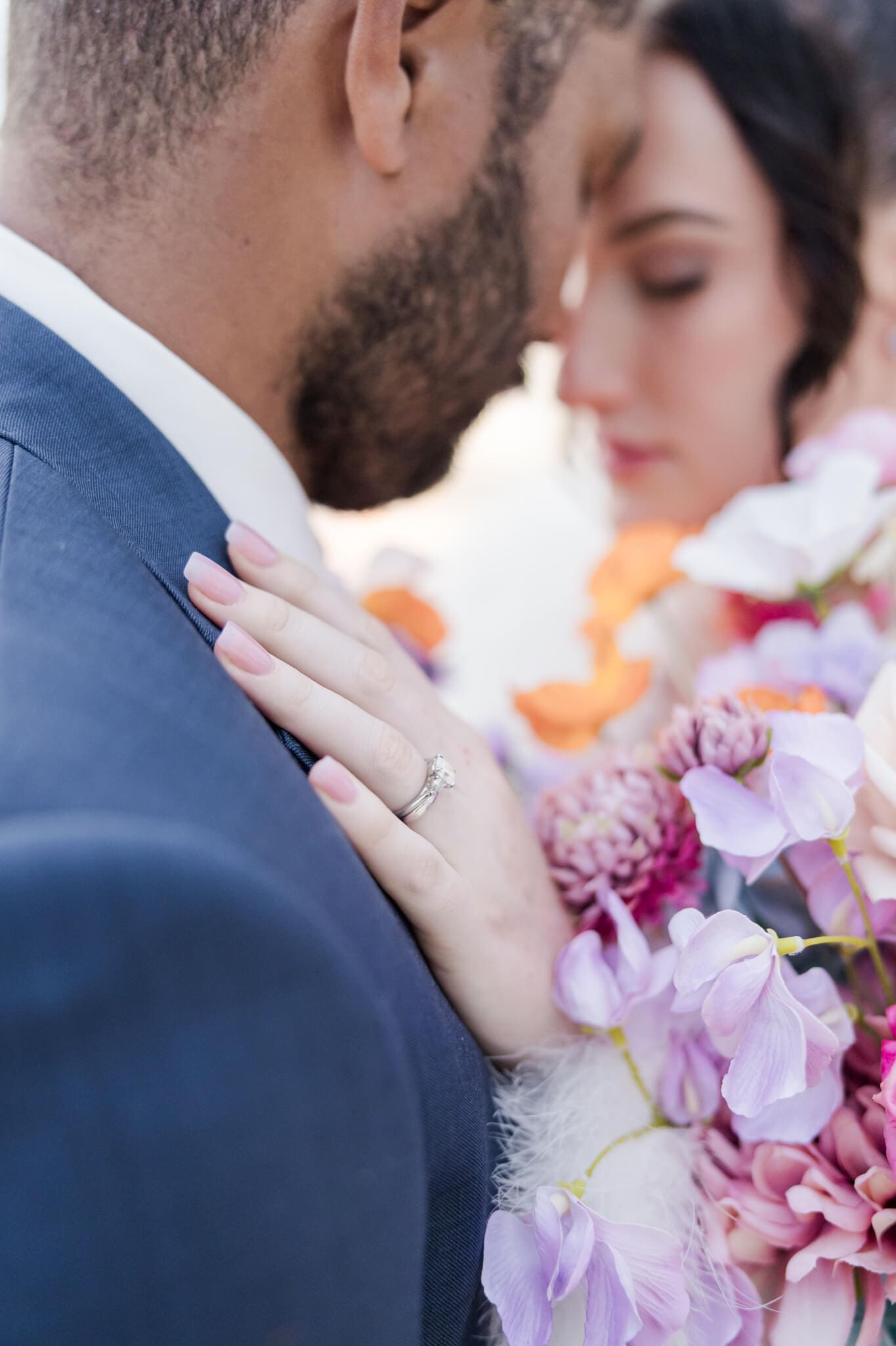 Close up shot of the bride and groom on their wedding day, show casing the ring and flowers.