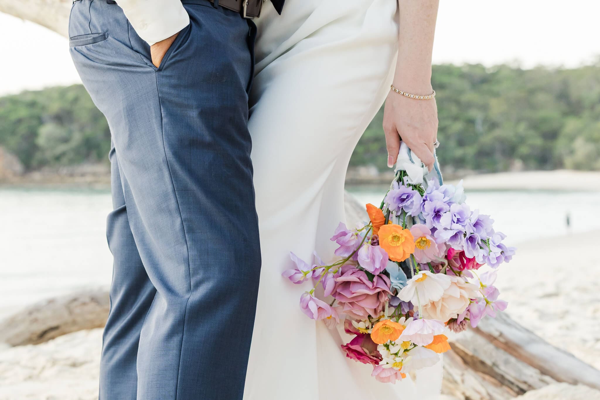 Close up shot of Bride and Groom as they embrace, of the bouquet on a beach at Great Keppel Island.