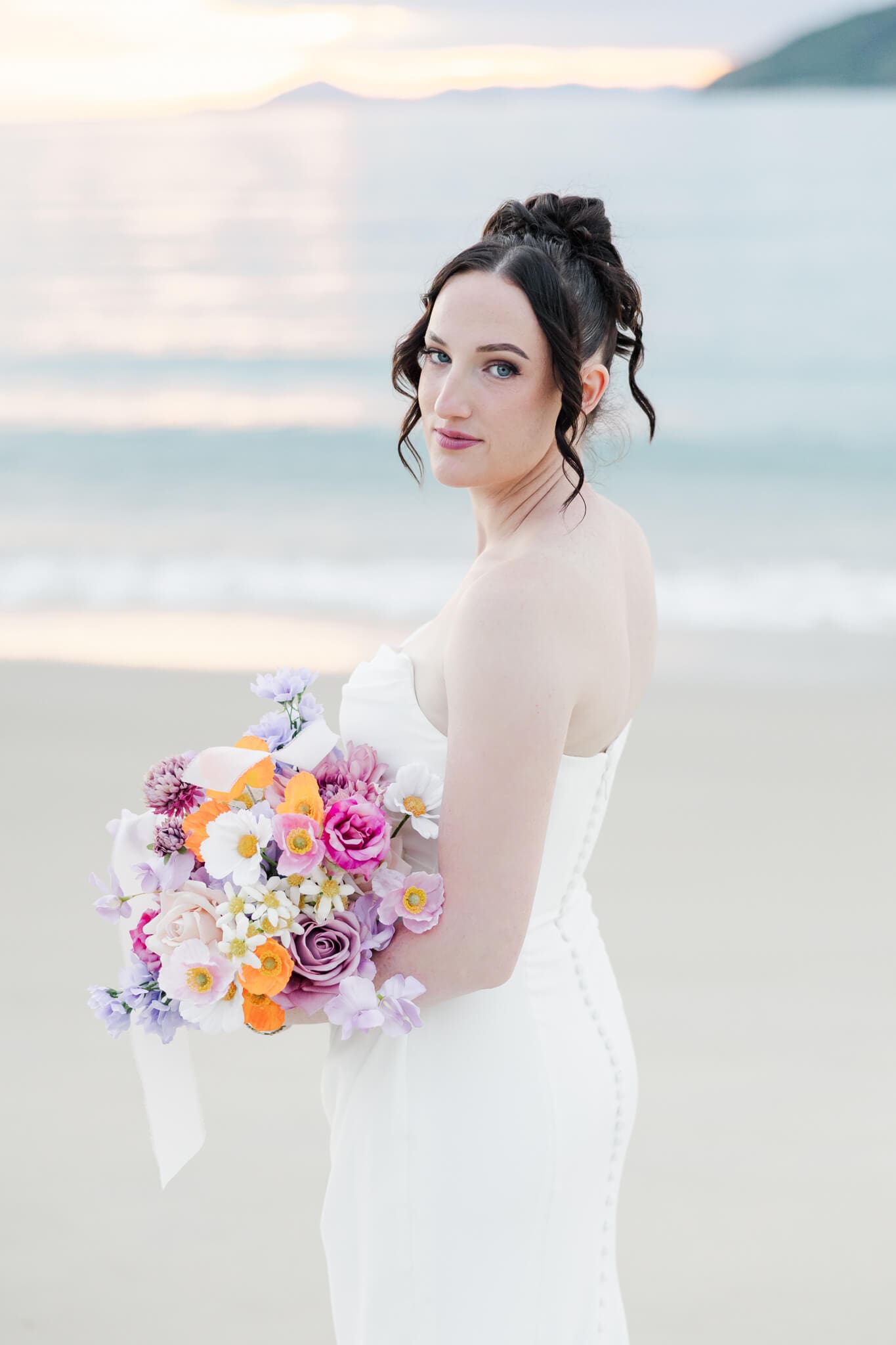 Bride poses for portrait on Great Keppel Island with a stunning sunset in the background.