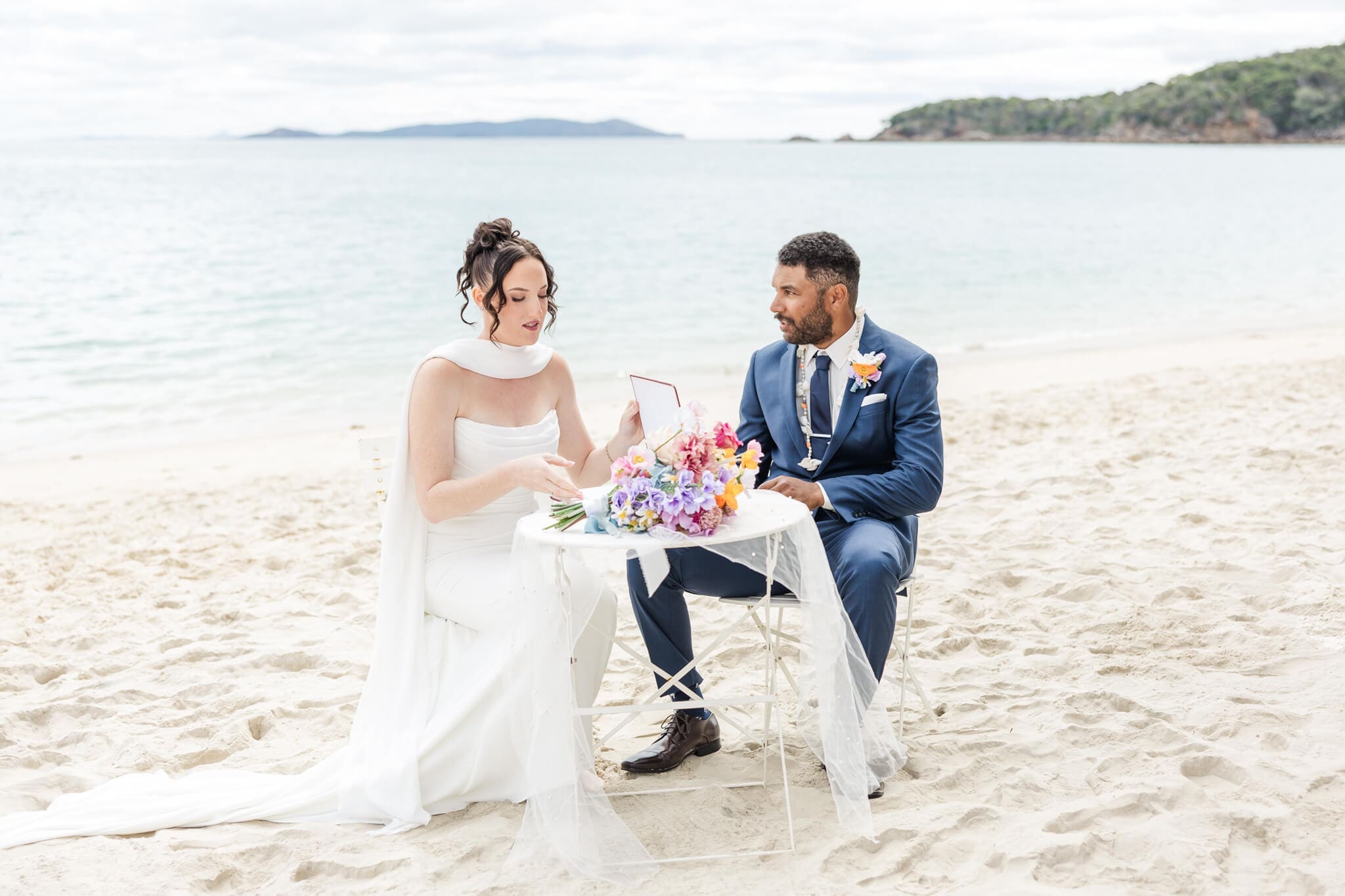 Wedding ceremony at the Great Keppel Island Hideaway, with the bride and groom signing the register in front of a beautiful blue ocean. Captured by Julie-Anne Photography.
