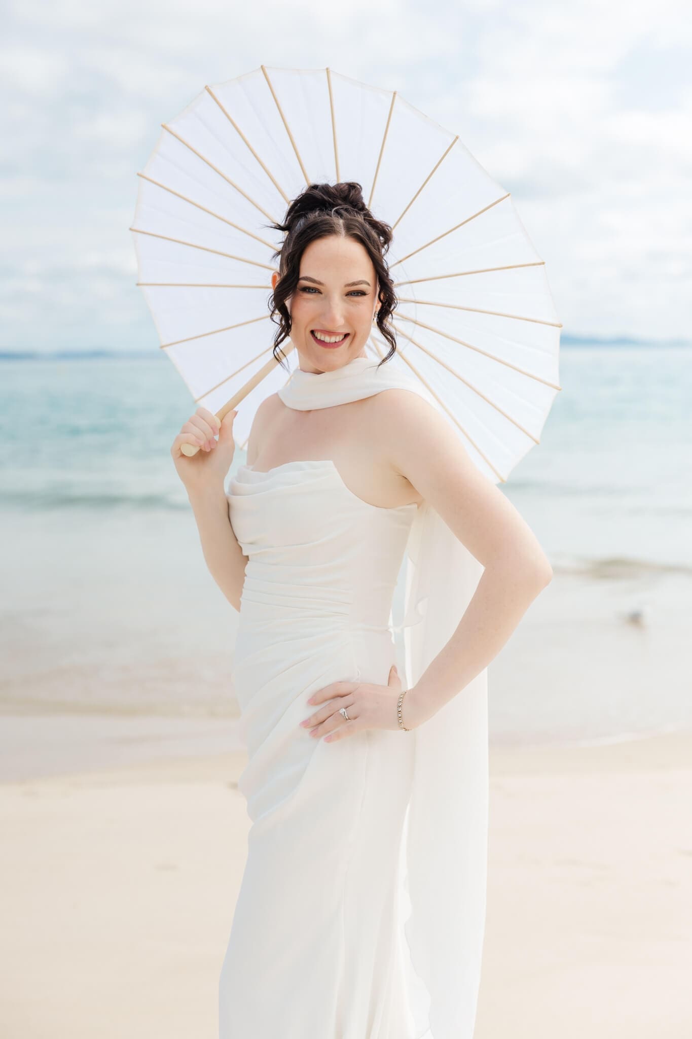 Portrait of a bride holding a paper parasol and posing on her wedding day. Located at Great Keppel Island Hideaway.