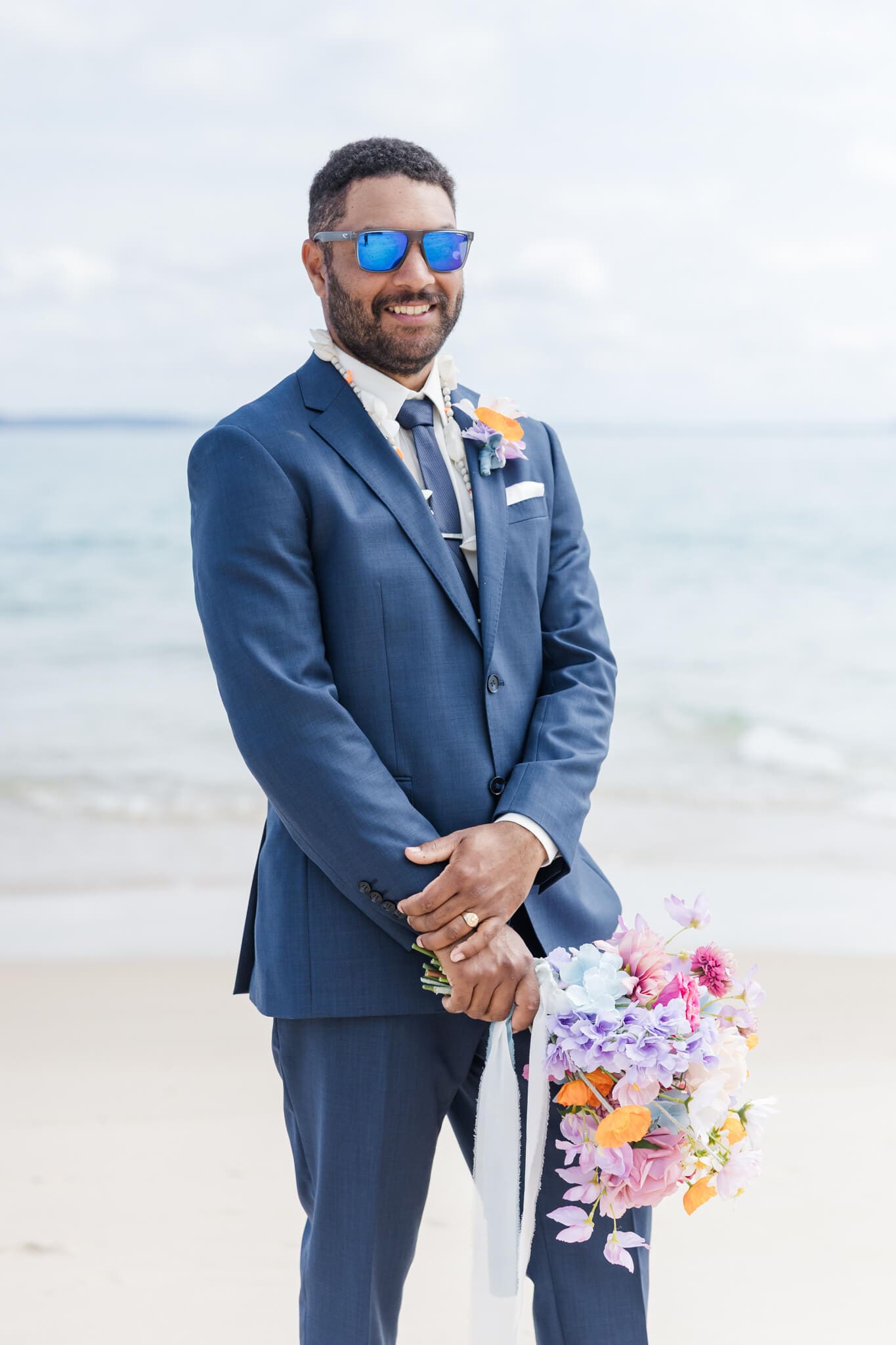 Groom with sunglasses on and holding the brides bouquet. Captured by Julie-Anne Photography, Yeppoon, Queensland.
