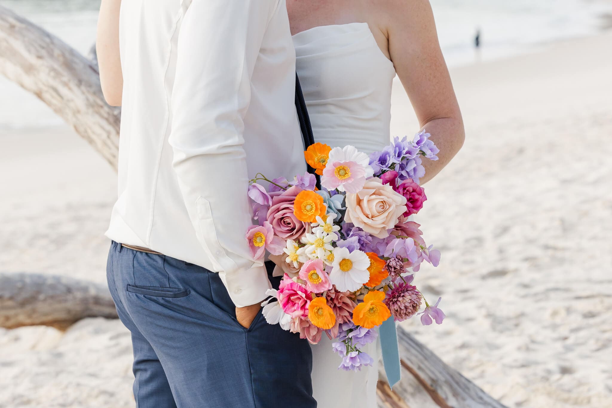Close up detail shot of brides bouquet as she holds it as the couple embrace.