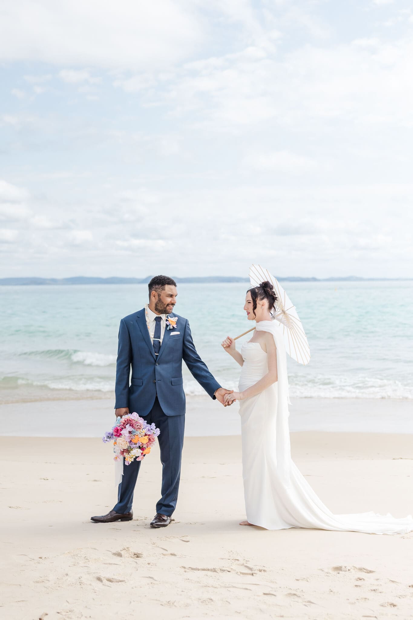 Wedding portrait of the bride and groom walking on the soft sand on the beach of Great Keppel Island. Wedding photos by Julie-Anne Photography, Yeppoon.