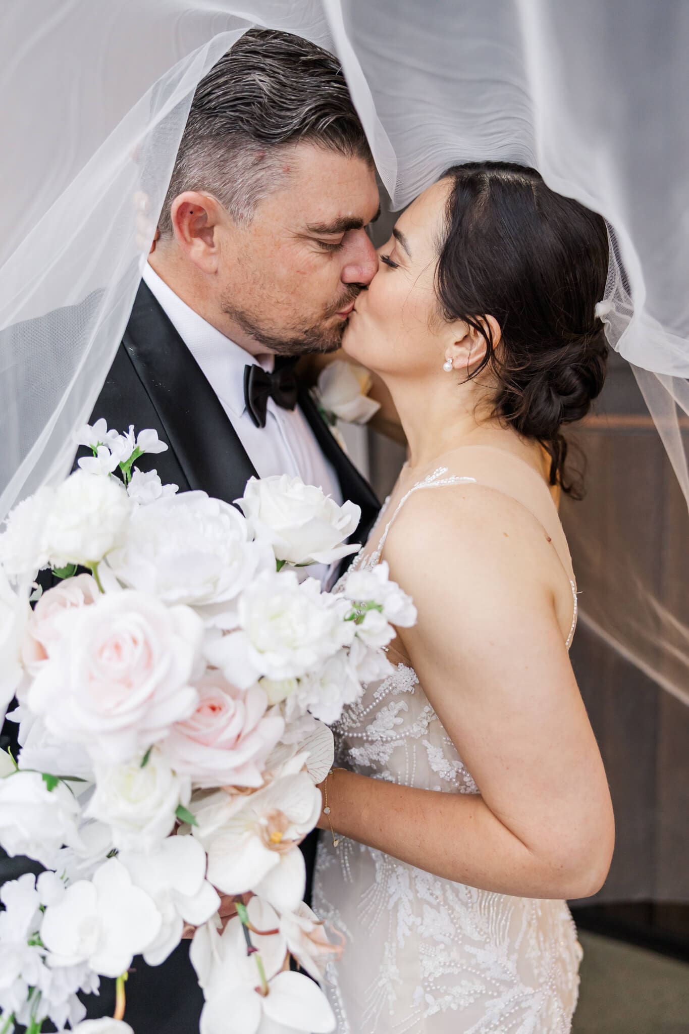 Bride and groom share a kiss under the veil. Located at Headricks Lane, Rockhampton wedding venue.