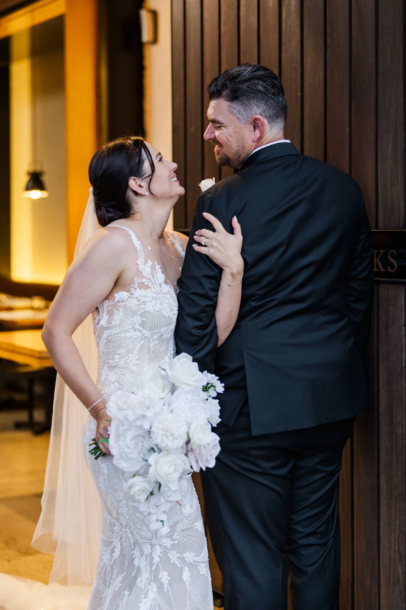Bride and groom looking affectionately at each other at their wedding venue entrance, Headricks Lane.