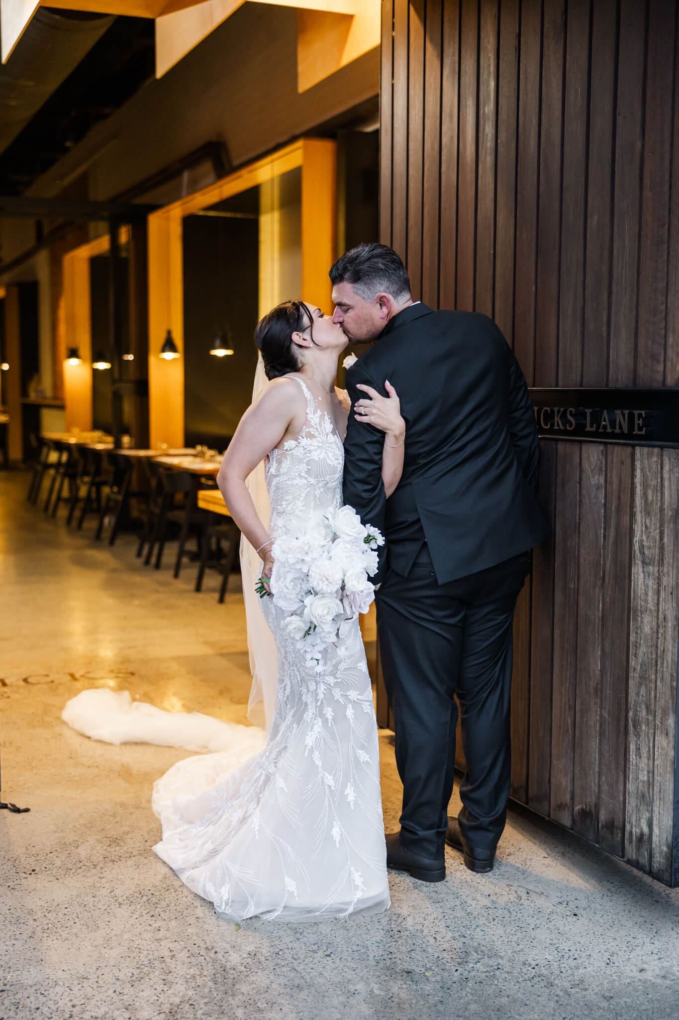 Bride and Groom stand at the entrance of Headricks Lane and share a kiss before their wedding reception.