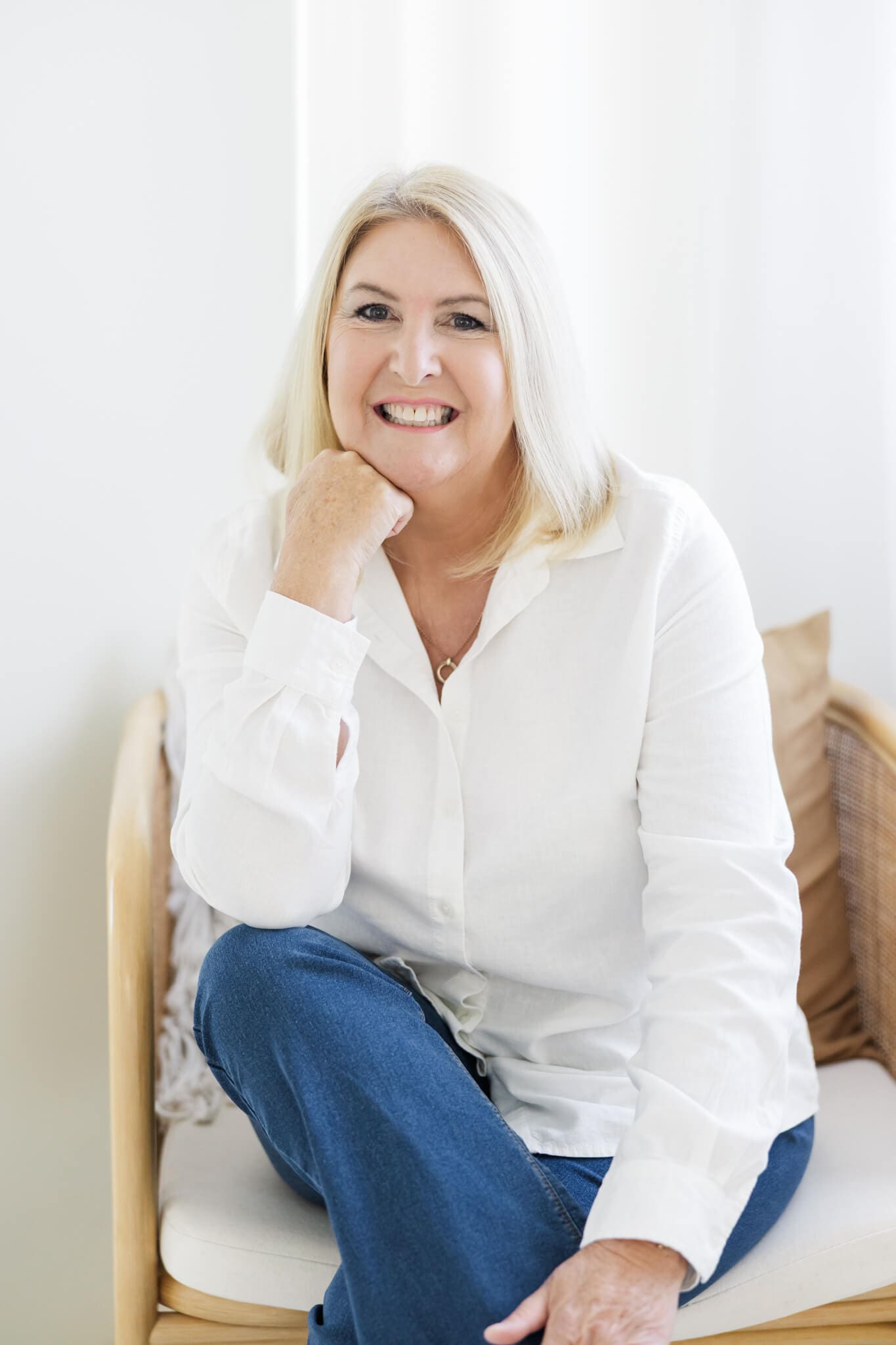 Branding photo of a marriage celebrant dressed in a white blouse and blue jeans, wearing a cream wide brimmed hat.