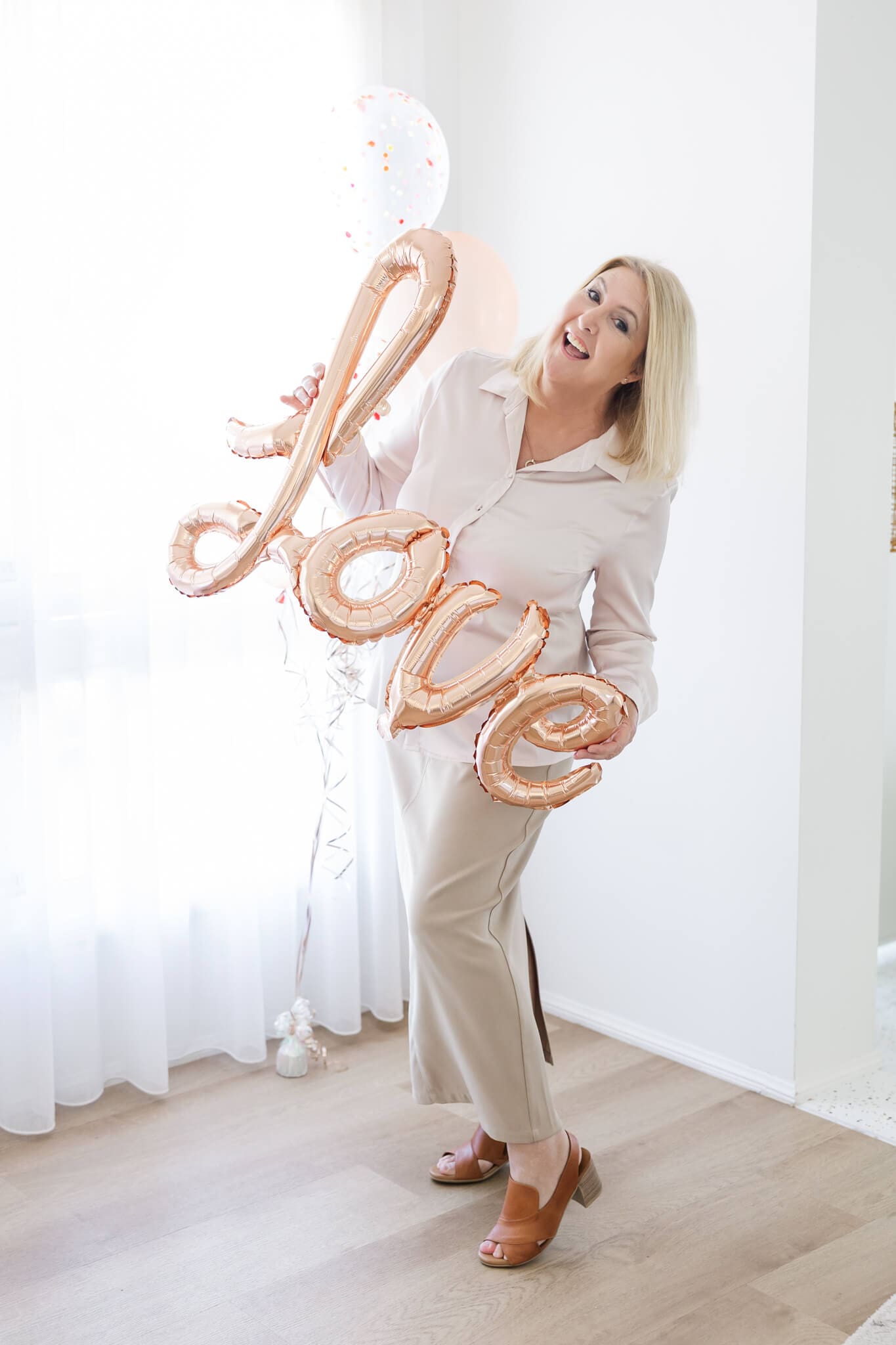 Ceremonies by Serena posing with a balloon that spells that word 'love'.