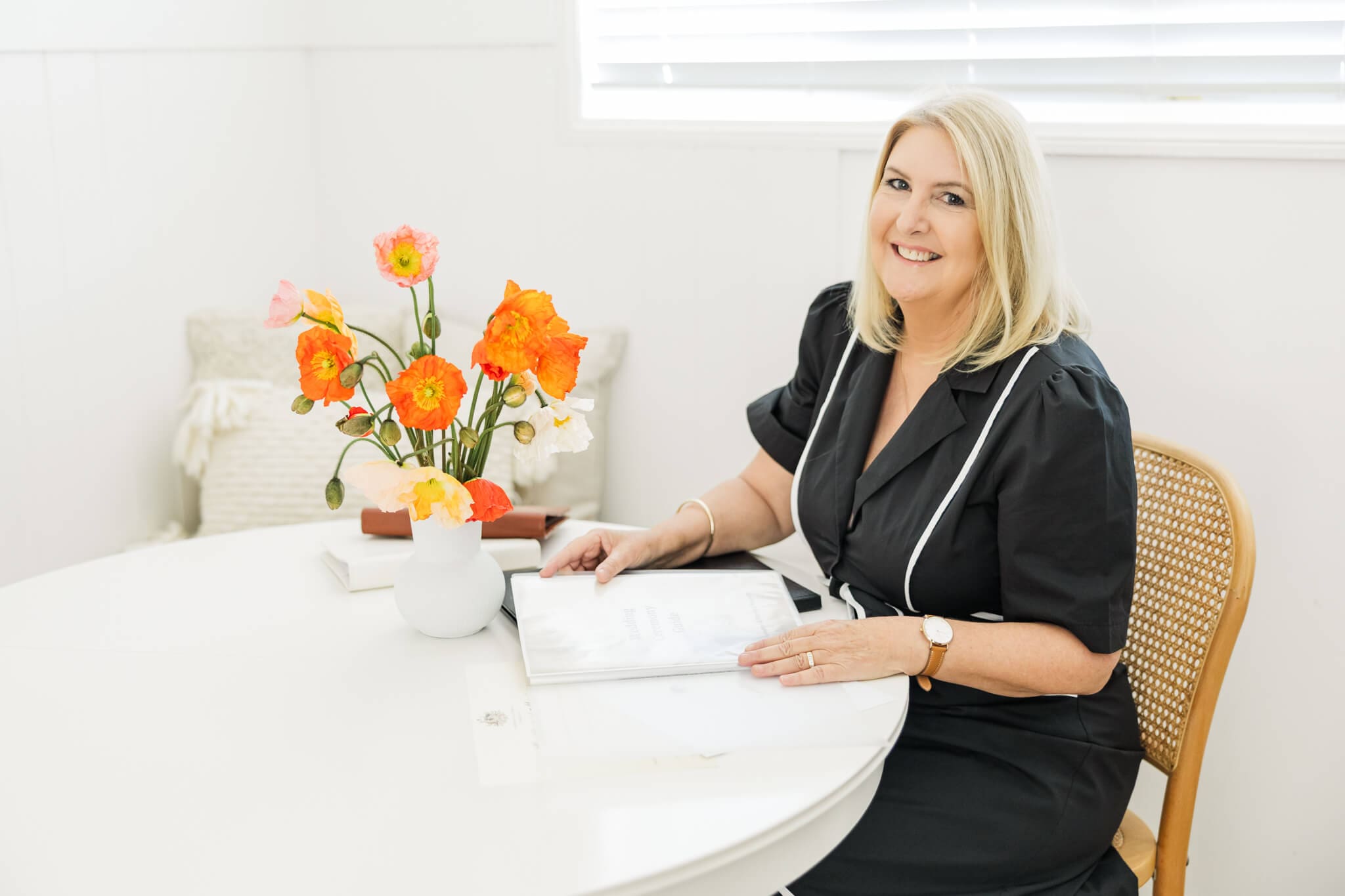 Branding portrait of Ceremonies by Serena, dressed in a black dress next to a gorgeous bunch of poppies in a vase.