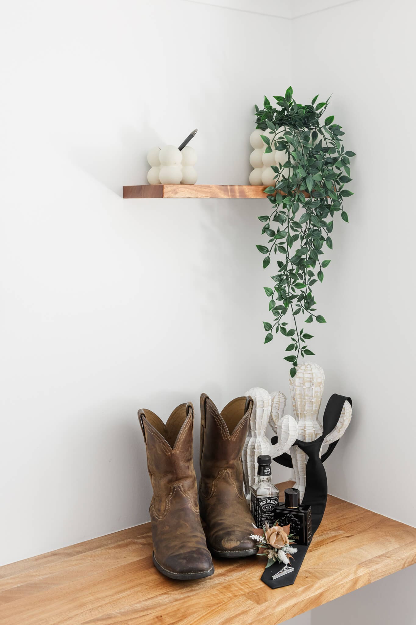 Detail shot of a groom's details including cowboy boots, a tie, a mini bottle of Jack Daniels whisky, cologne and a boutonniere.