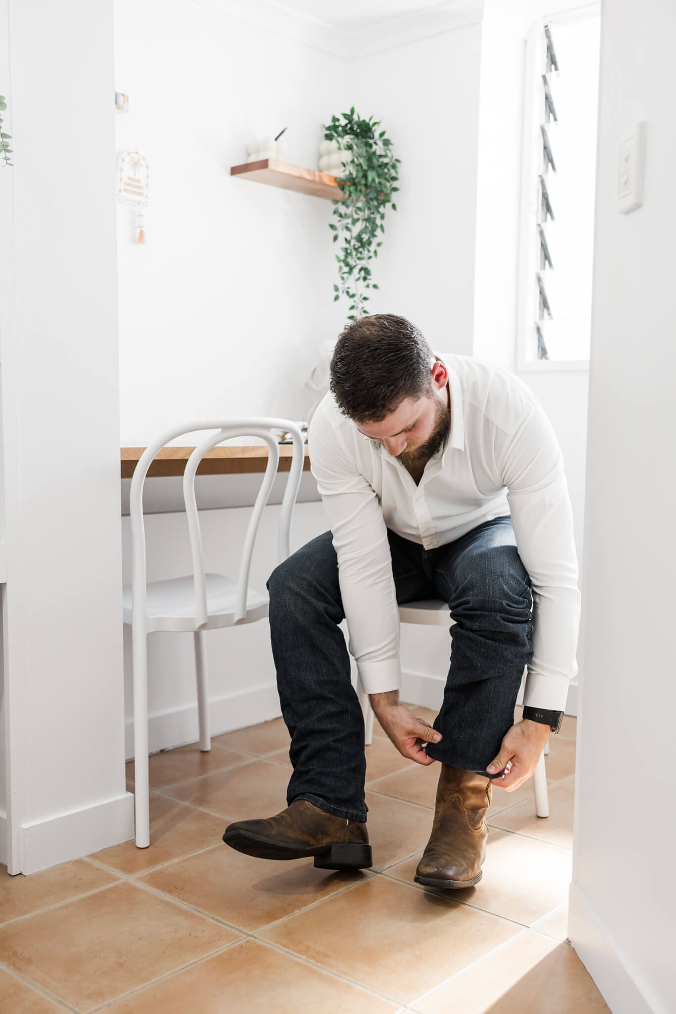 Groom puts on his boots as he gets ready for his wedding ceremony.