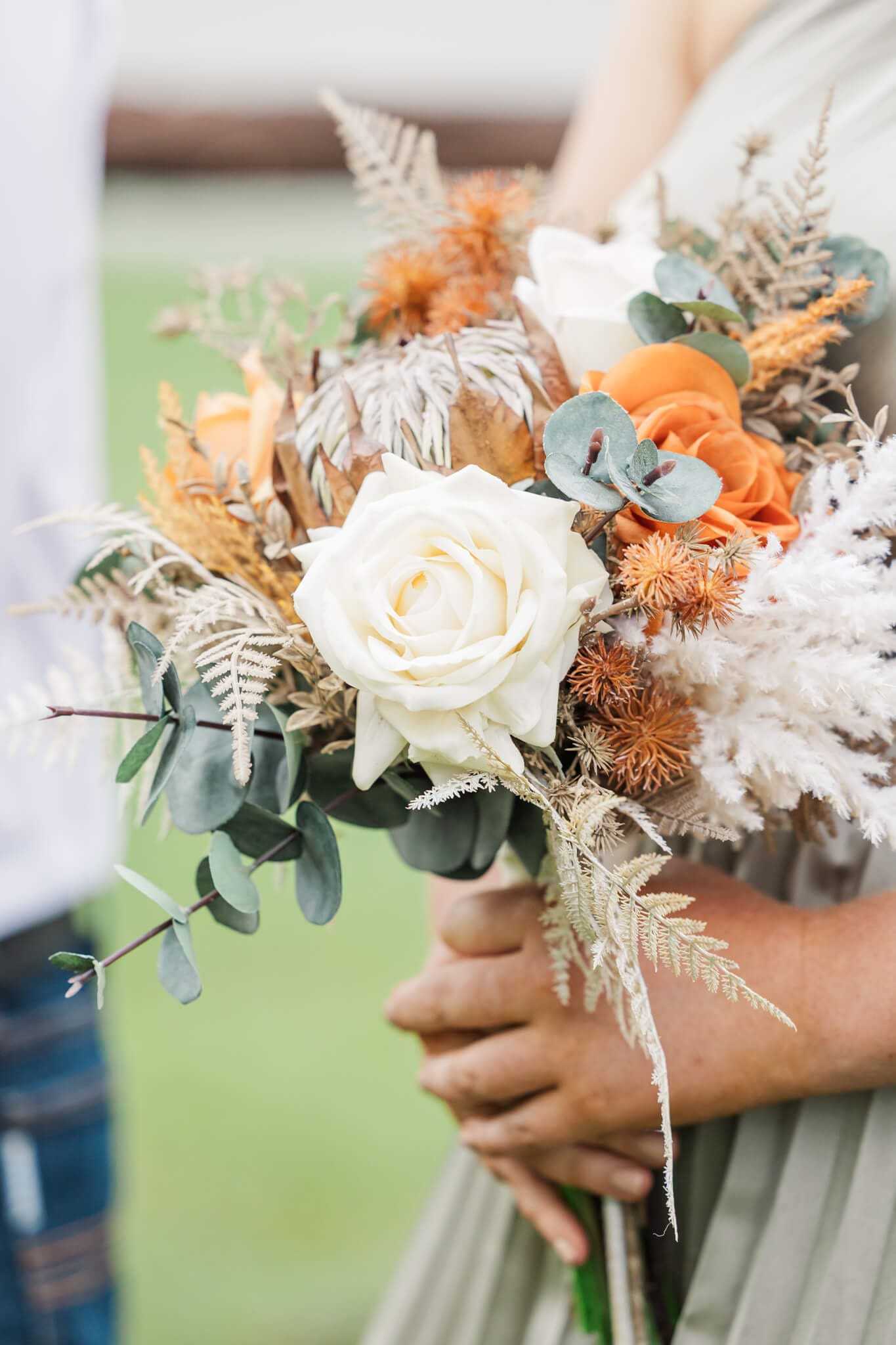 Beautiful bridal bouquet with orange and brown touches amongst sprigs of wattle. Close up detail shot.