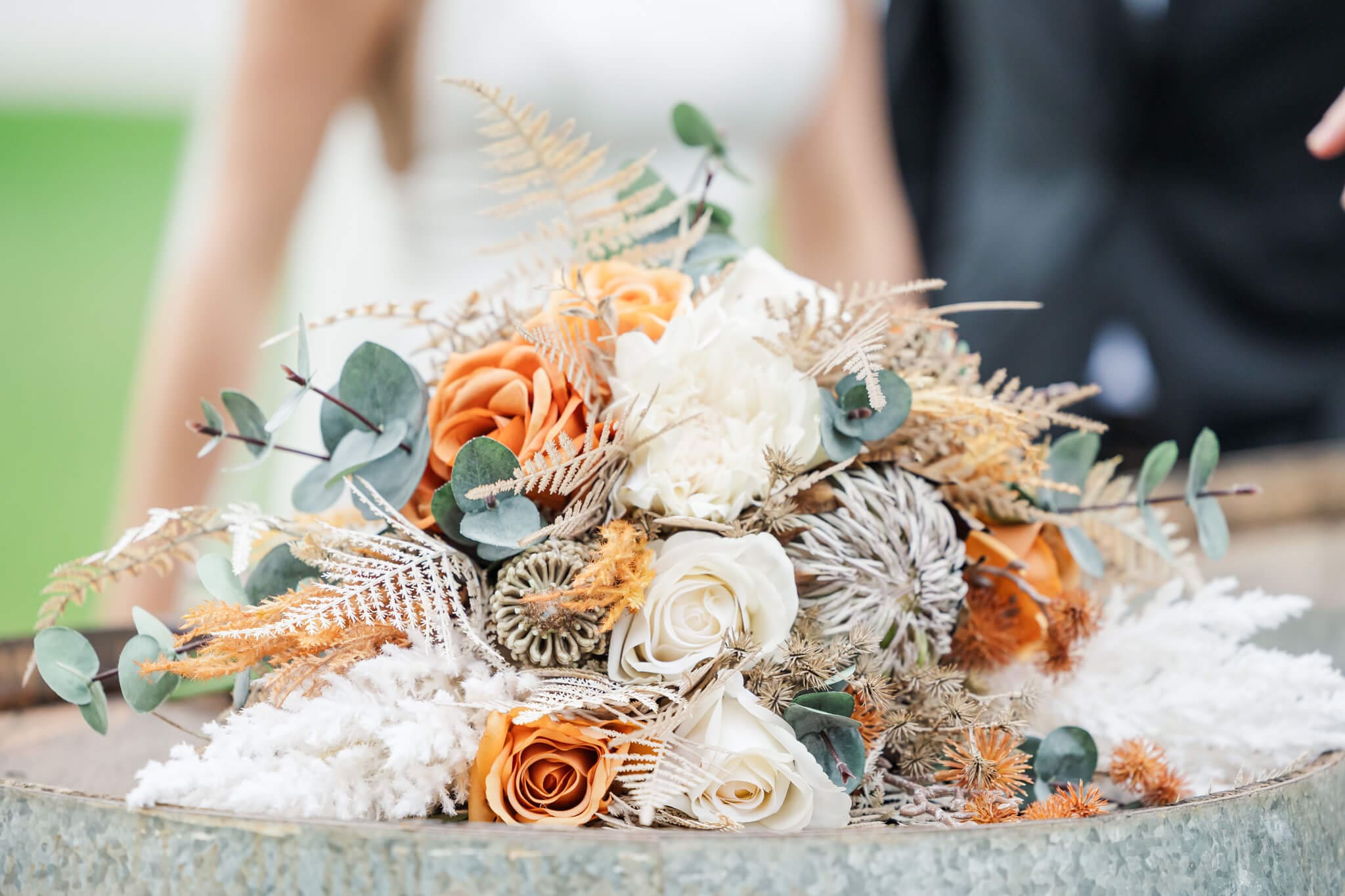 Beautiful bridal bouquet with orange and brown touches amongst sprigs of wattle. Close up detail shot.