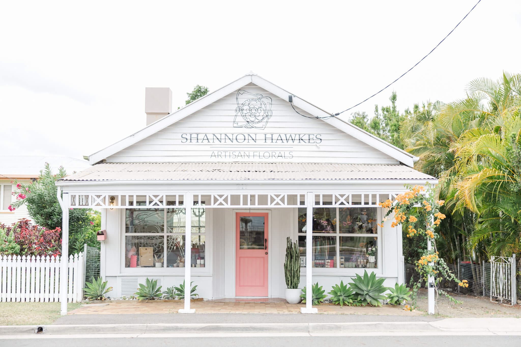 Cute little florist in Rockhampton with a pink door and gorgeous plants around it's white building.