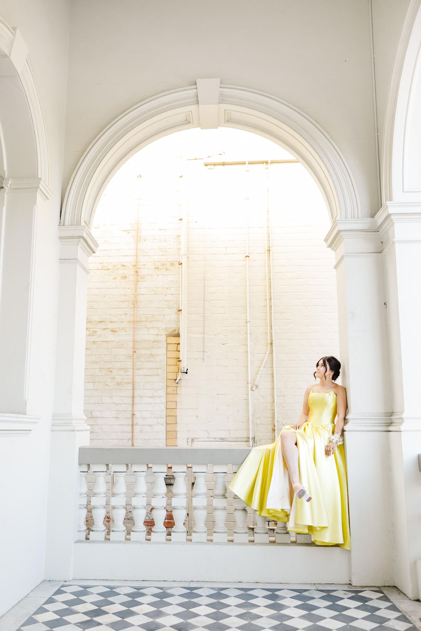 Beautiful girl in a yellow dress posing for her formal with a corsage on her hand. Captured by Julie-Anne Photography.