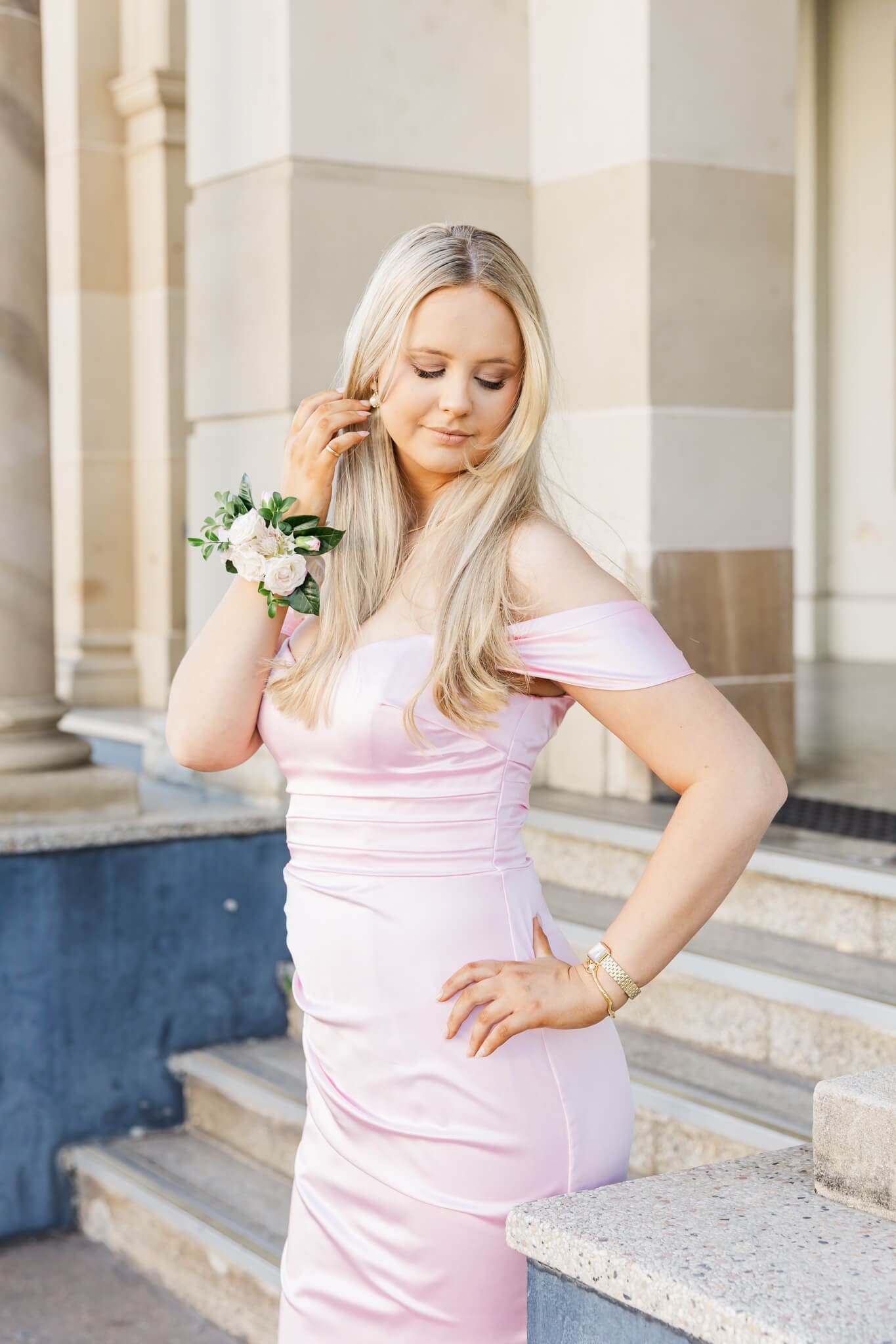 Beautiful blonde haired girl in her graduation formal dress, tucking her hair behind her ears with a stunning floral arrangement on her wrist, created by Shannon Hawkes Rockhampton.