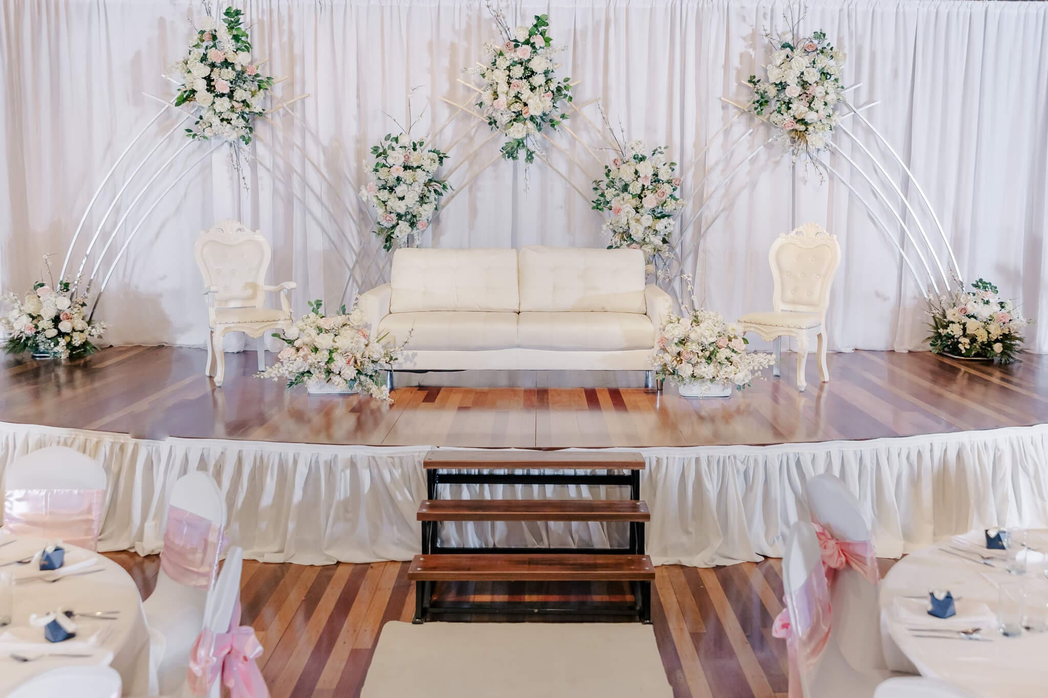 Beautiful styling by a wedding hire Rockhampton business, Stylish Events and Hire. A white chair and sofa surrounded by white, pink and cream florals.