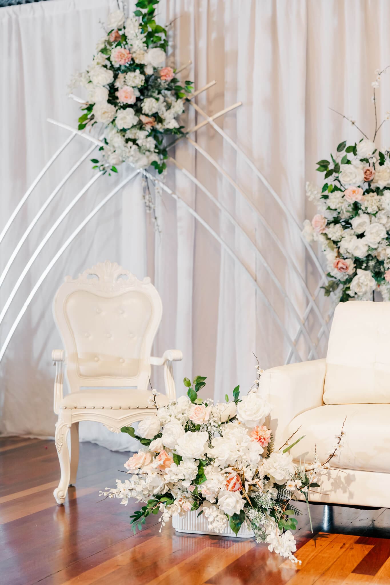 Beautiful styling by a wedding hire Rockhampton business, Stylish Events and Hire. A white chair and sofa surrounded by white, pink and cream florals.
