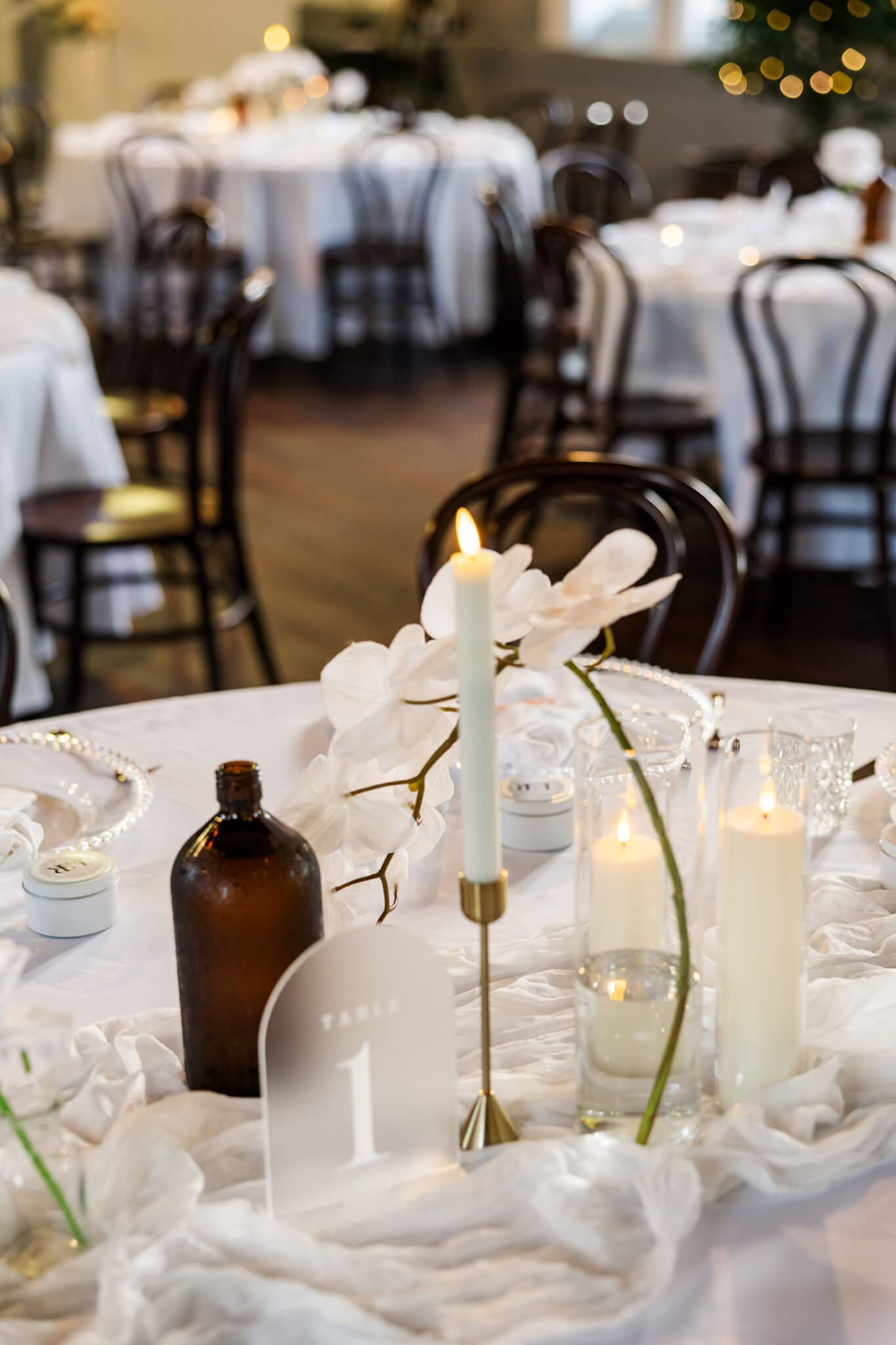 Wedding reception tables decorated with napkins, table linen, vases, florals and candles.