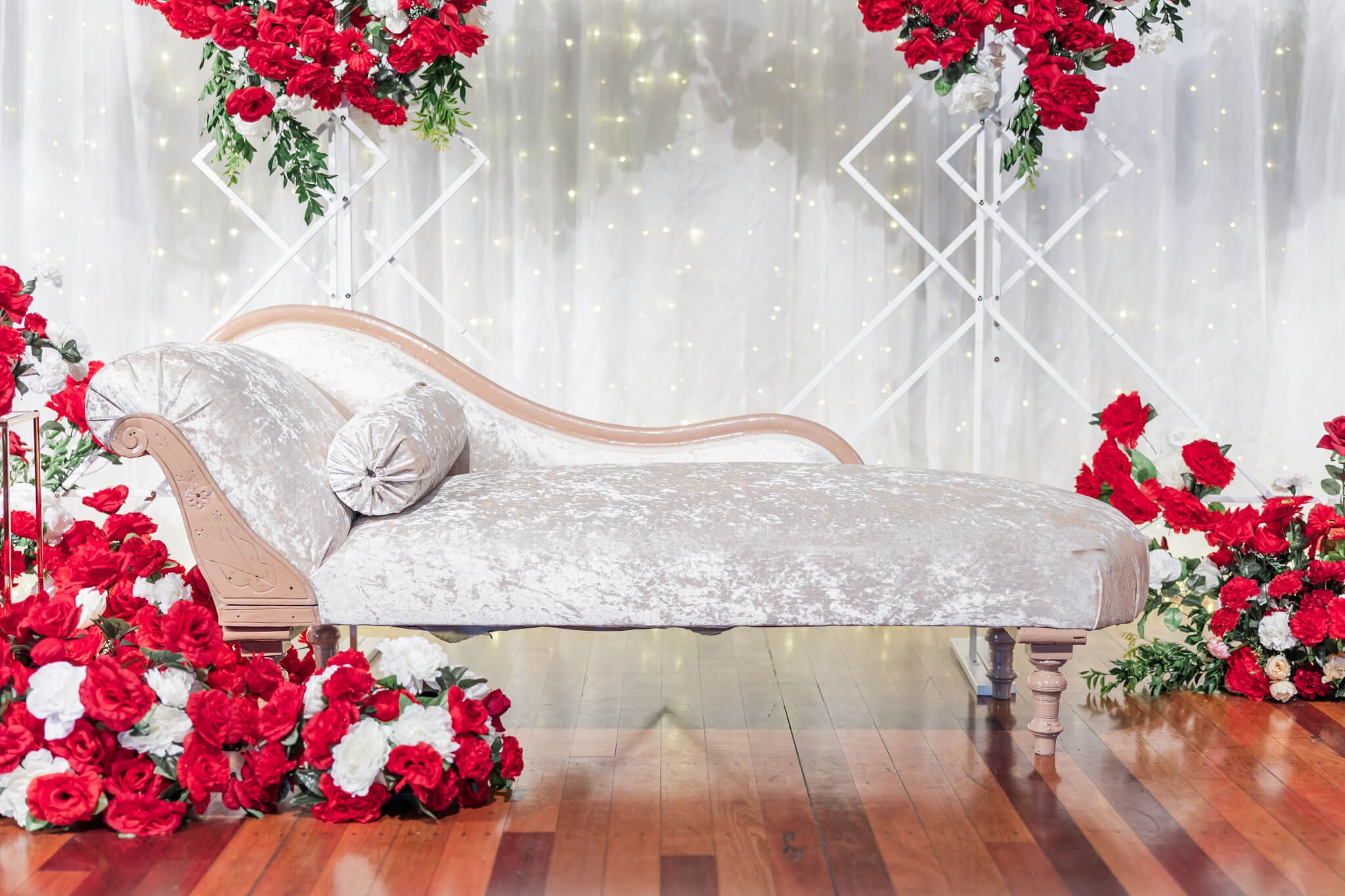 Stunning arrangements created by Lilly and Lotus Rockhampton for a wedding. A sofa bed surrounded by red and white florals.
