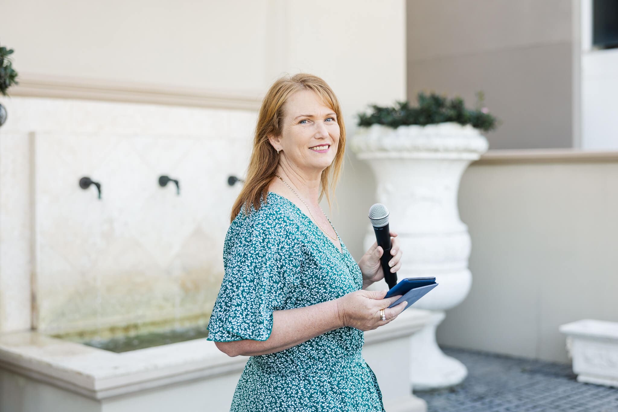 Wedding Celebrant Heather Sanders ready with her microphone in a green dress at a beautiful wedding venue.