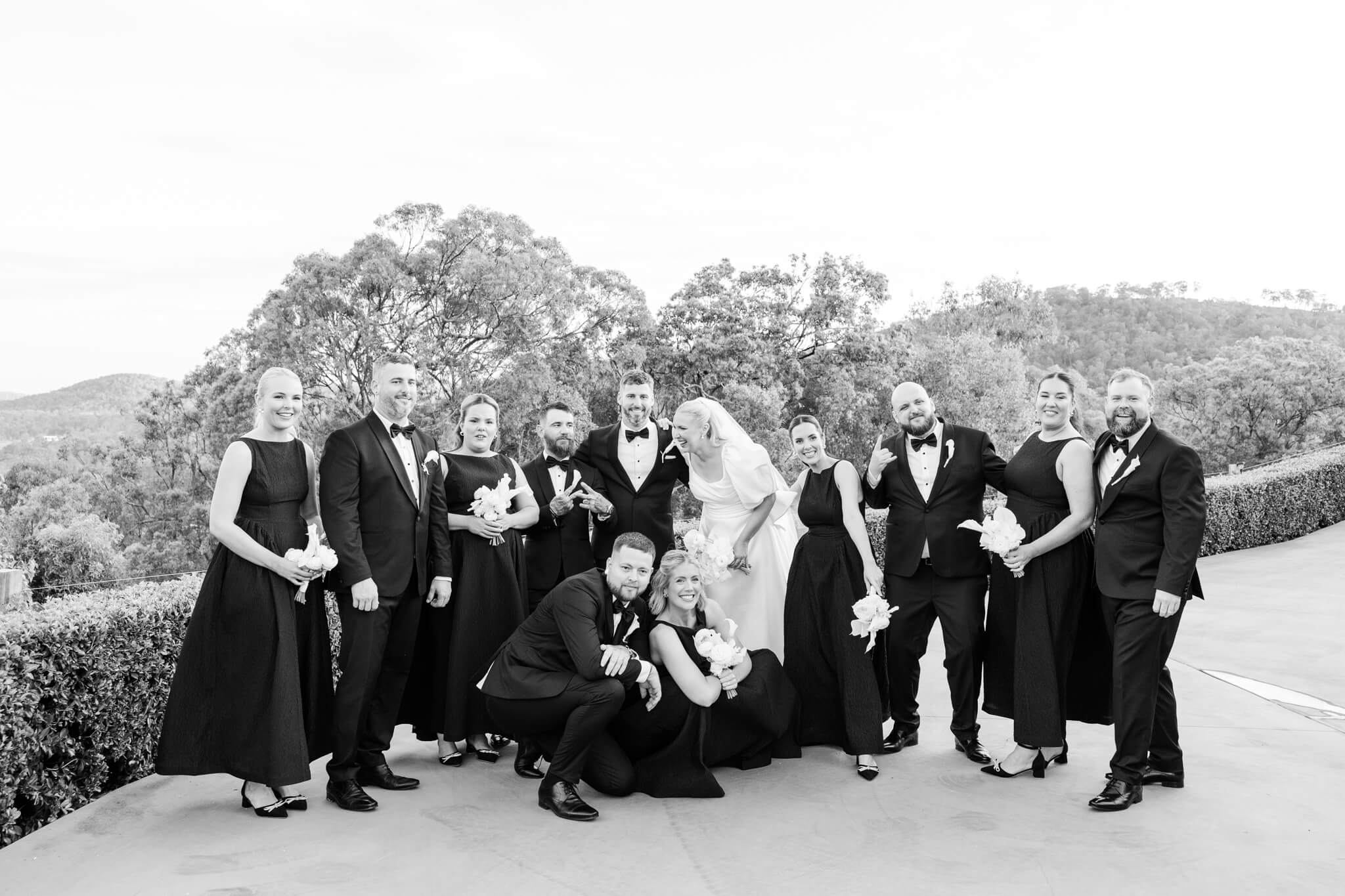 Black and white editorial wedding photo of a very bridal party, candidly playing around in a group.