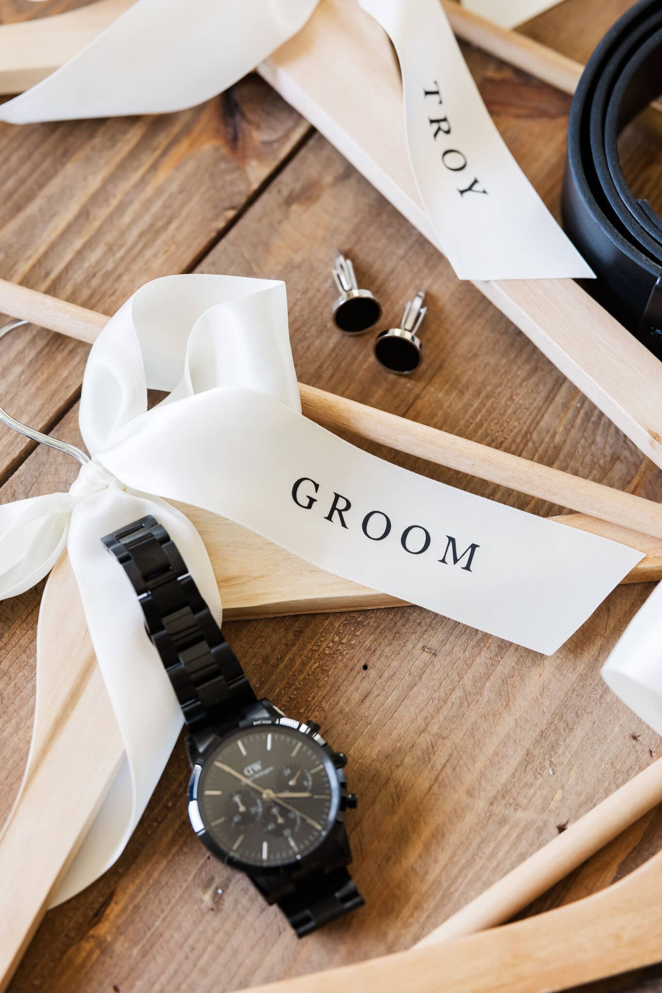 Editorial wedding photography style detail shot of the grooms details including cuff links, a watch and personalised coat hangers.